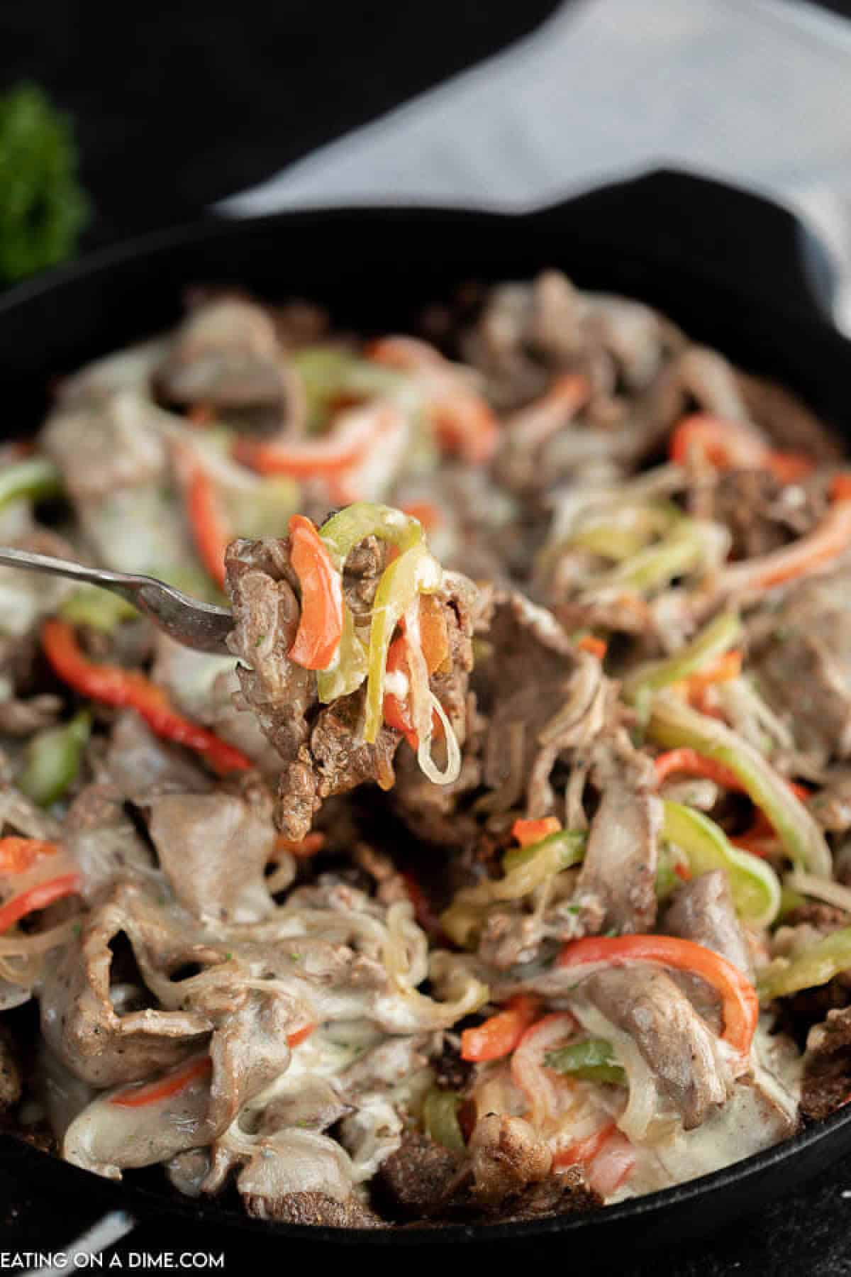 Close up image Philly Cheese Steak in a skillet. Serving on a fork. 