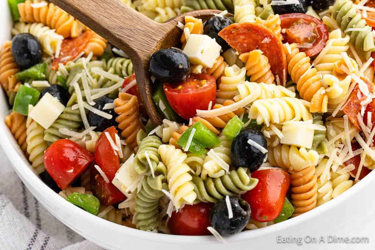 Italian Pasta Salad in a bowl with serving on a wooden spoon
