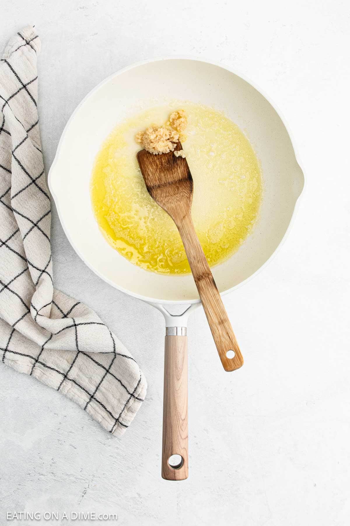 Melted butter in a skillet with minced garlic with a wooden spoon