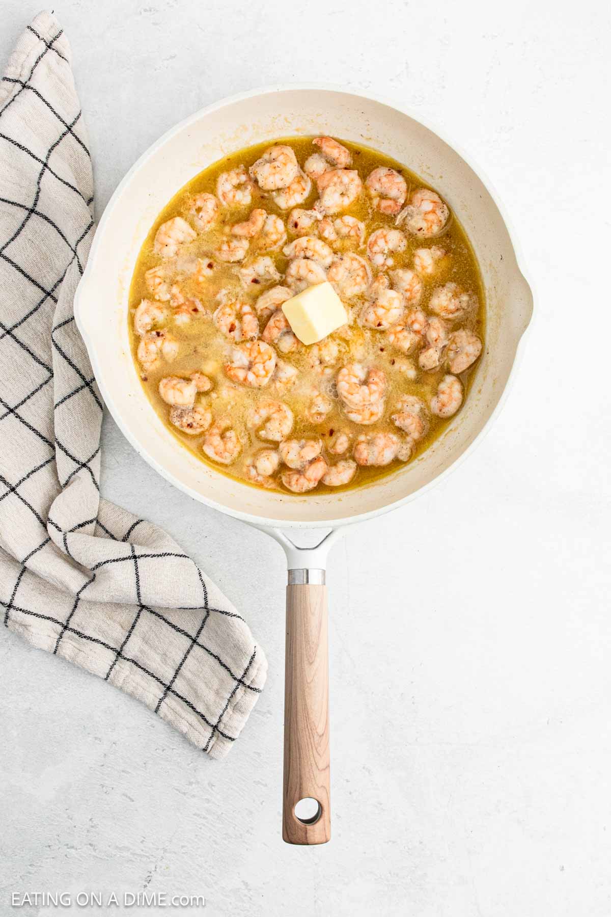 Shrimp in a melted butter mixture in a skillet