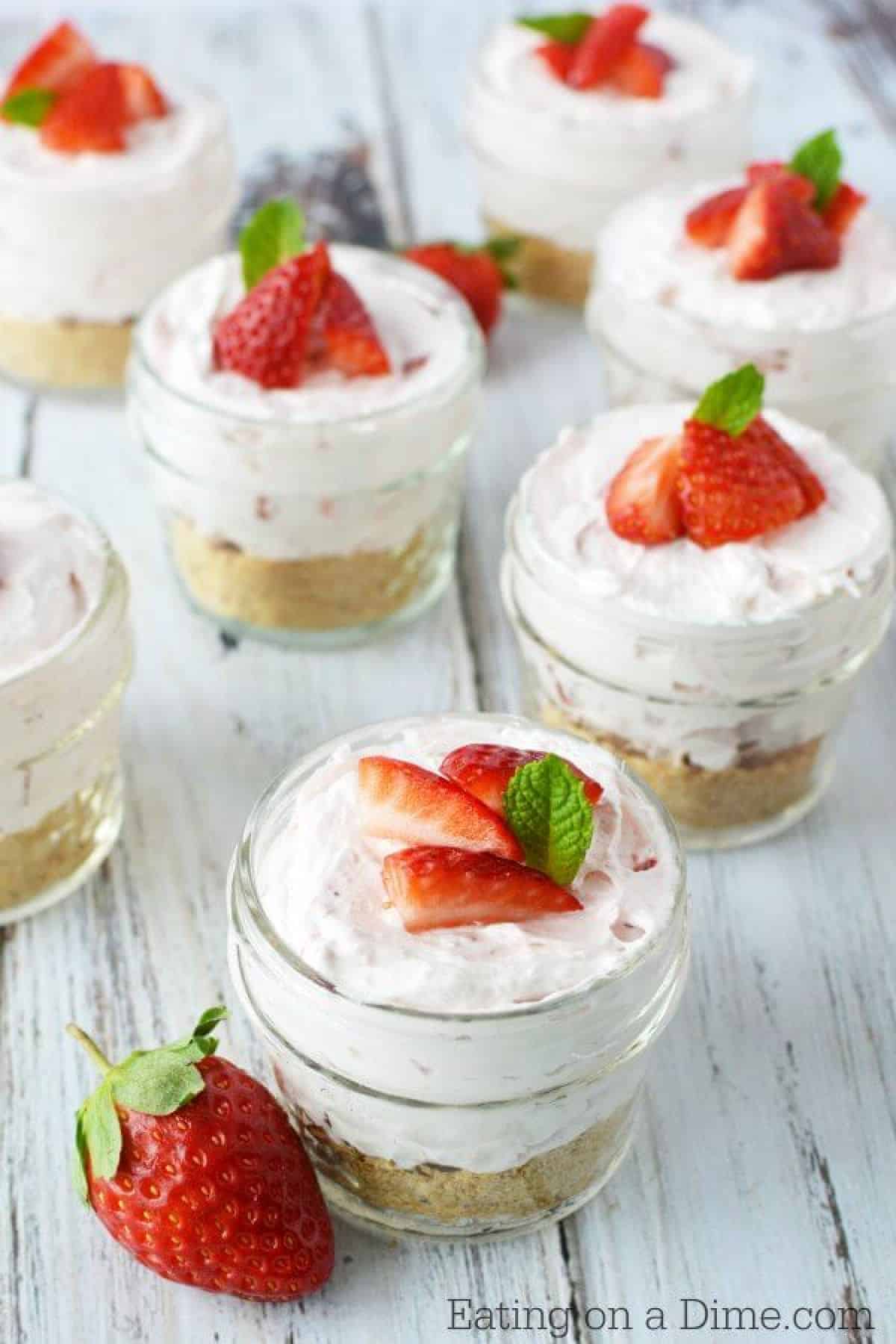 Close up image of cheesecake in a jar topped with strawberries. 