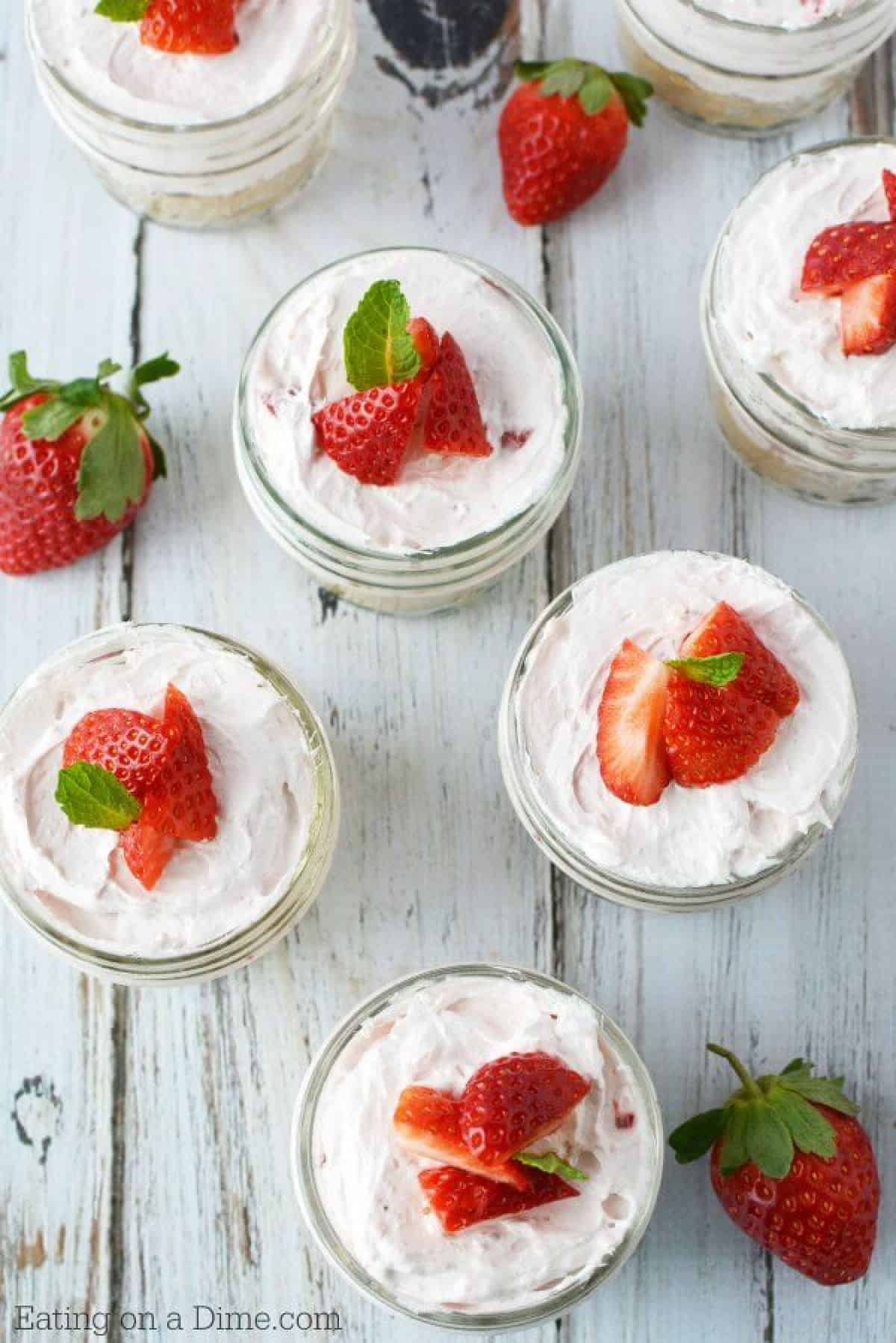 Close up image of cheesecake in a jar topped with strawberries. 