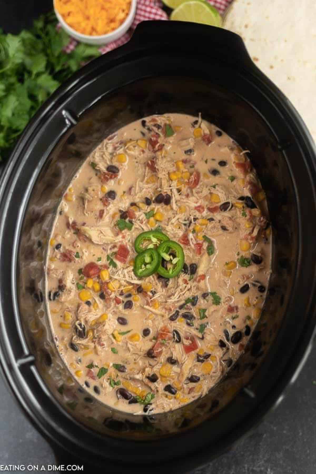 Close up image of fiesta chicken in the crock pot with a wooden spoon. 