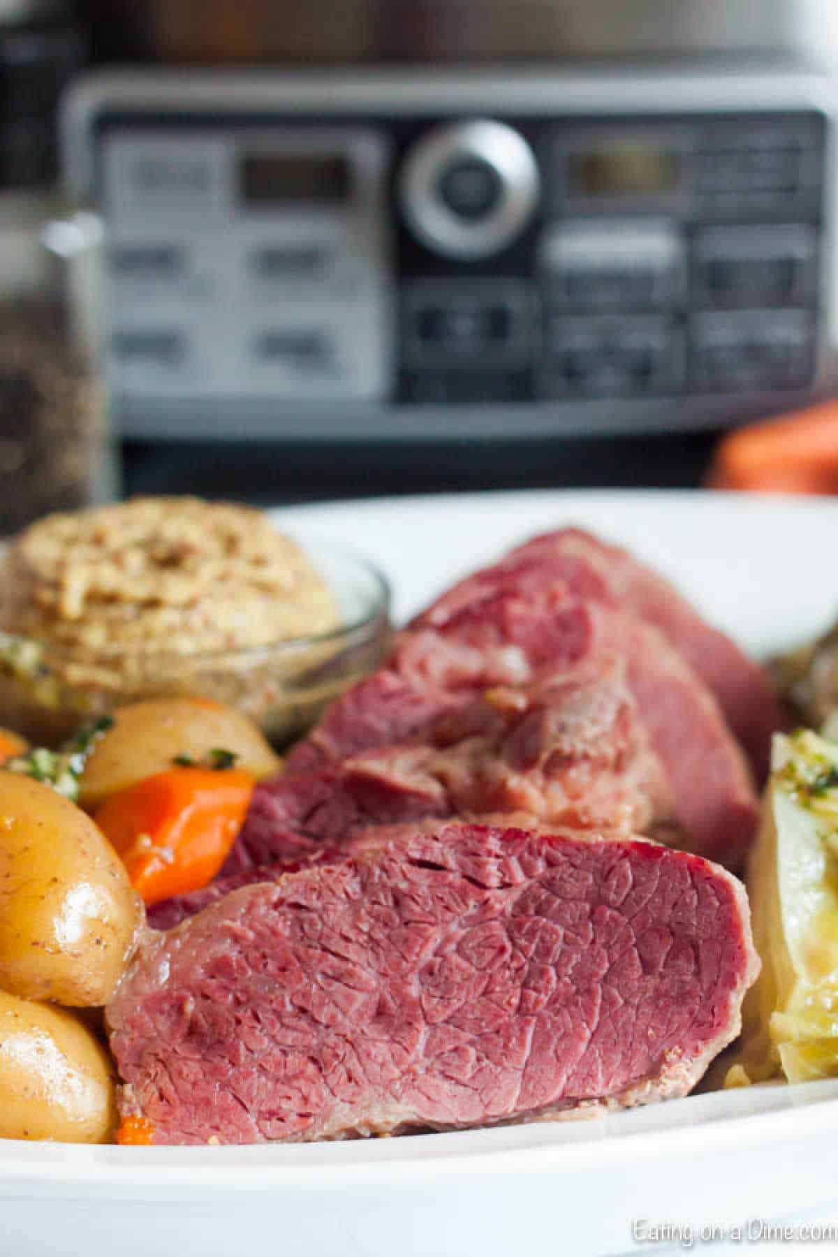 Sliced corn beef on a platter with cooked potatoes and carrots 