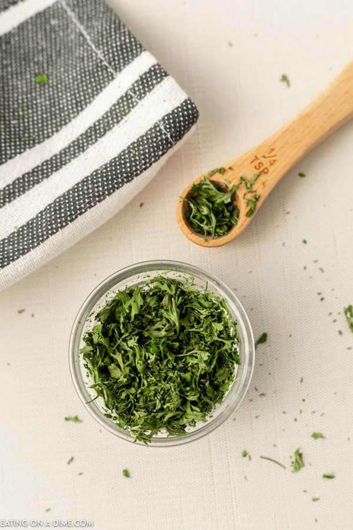 Close up image of dried parsley in a bowl with a ¼ teaspoon of dried parsley.