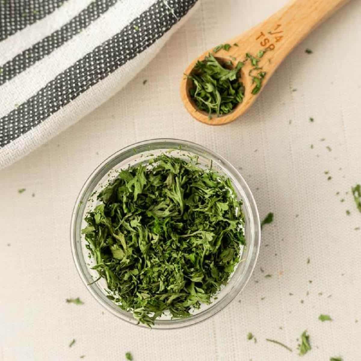 Close up image of dried parsley in a bowl with a ¼ teaspoon of dried parsley.