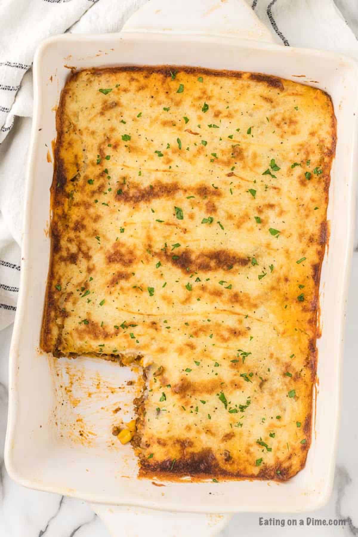 Close up image of Shepherd's Pie in a 9x13 baking dish with a piece missing. 