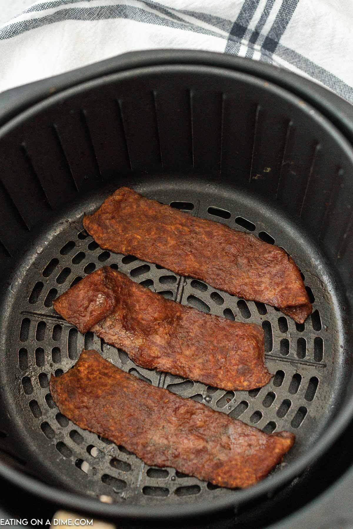 Cooked strips of turkey bacon in the air fryer basket