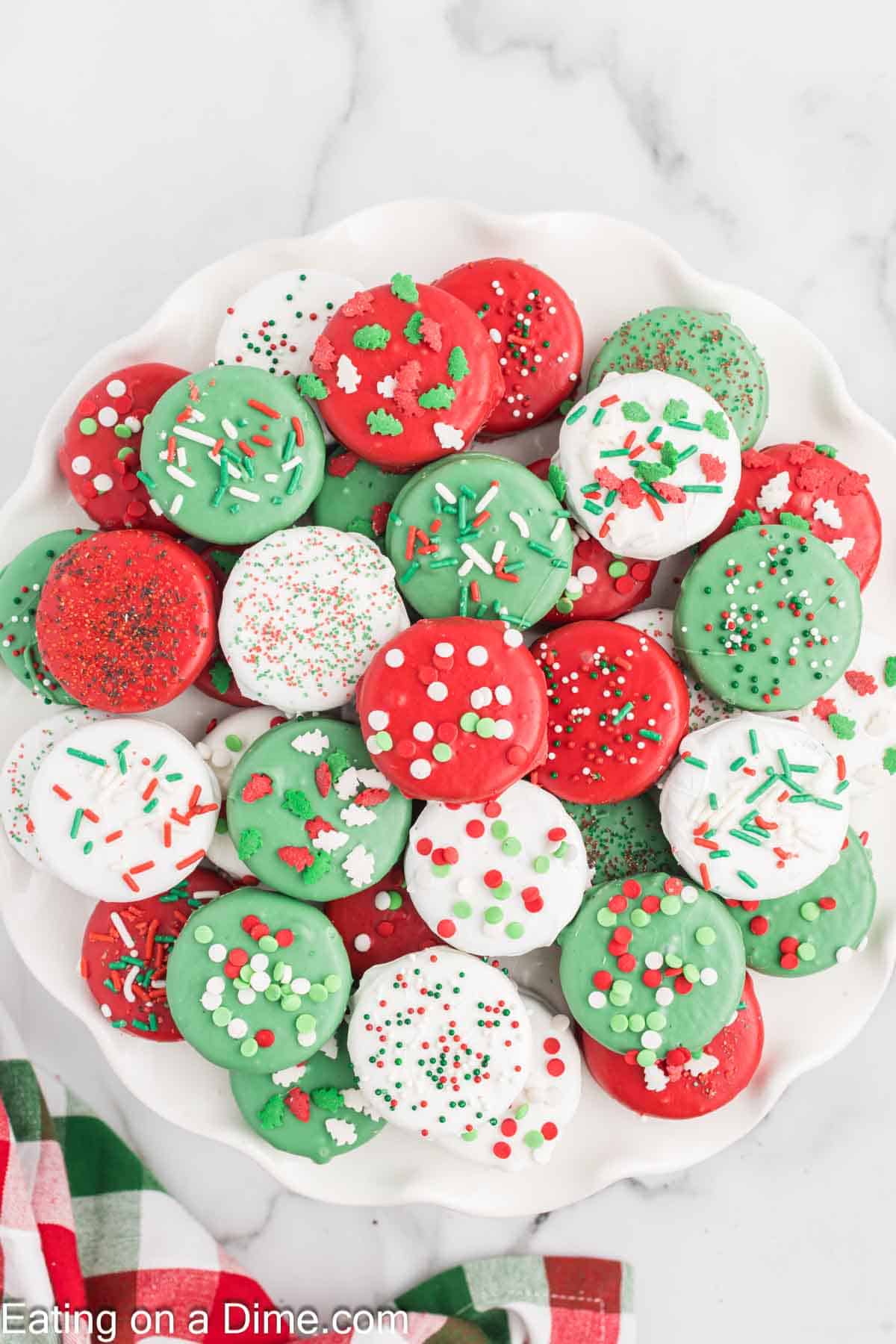 Red, Green, White Chocolate Covered Oreos topped with red and green sprinkles stacked on a platter