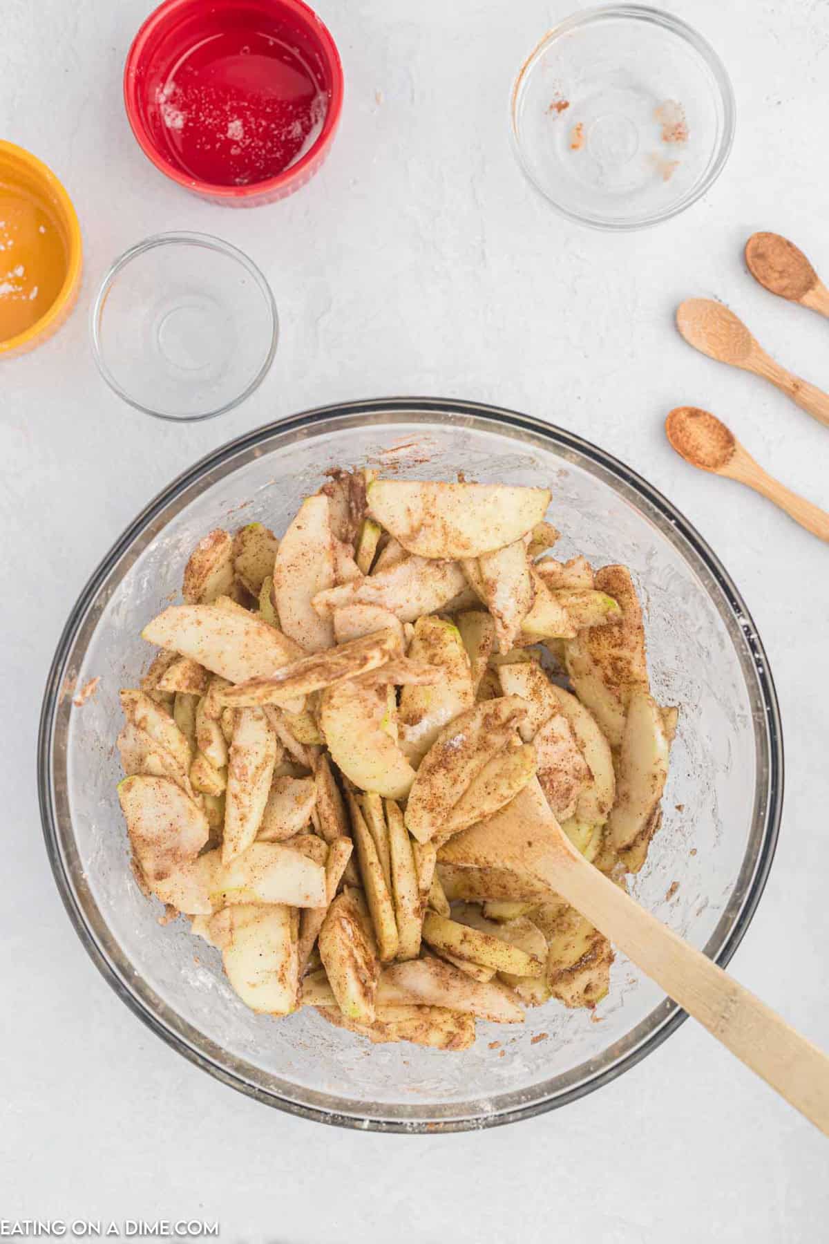 Slice apples in a bowl mixed with spices with a wooden spoon