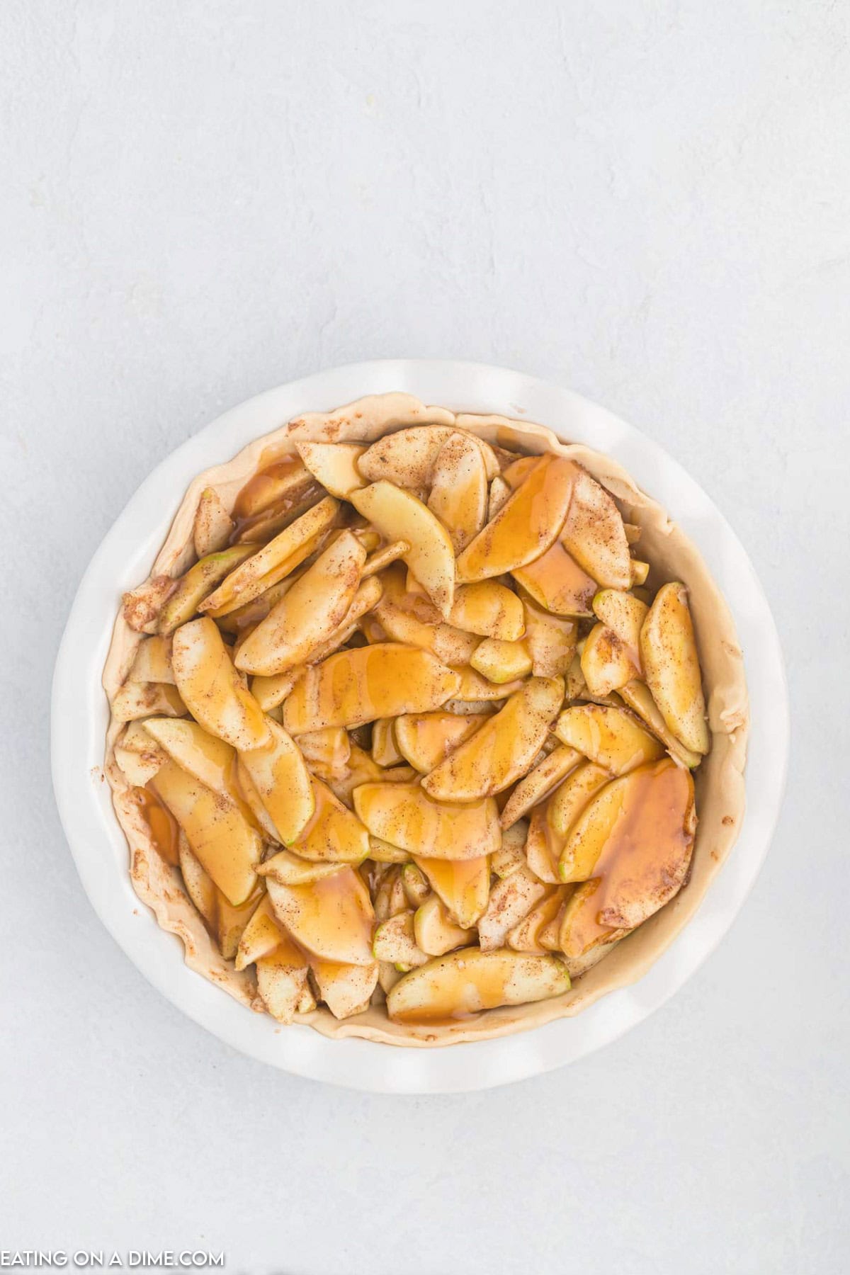 Seasoned sliced apples placed in a pie plate and drizzled with caramel sauce