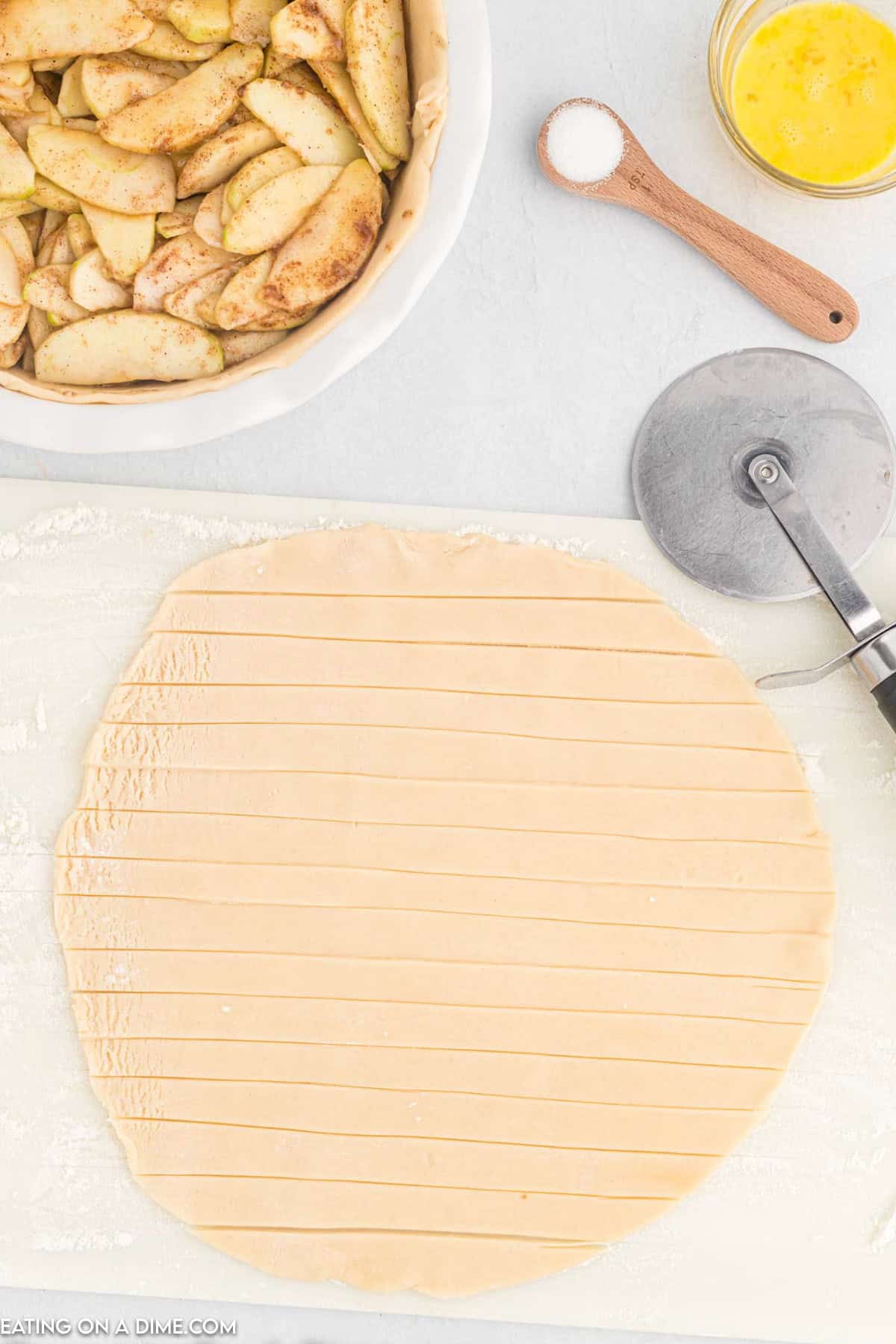 Pie dough placed on parchment paper and cut into strips with a pizza cutter