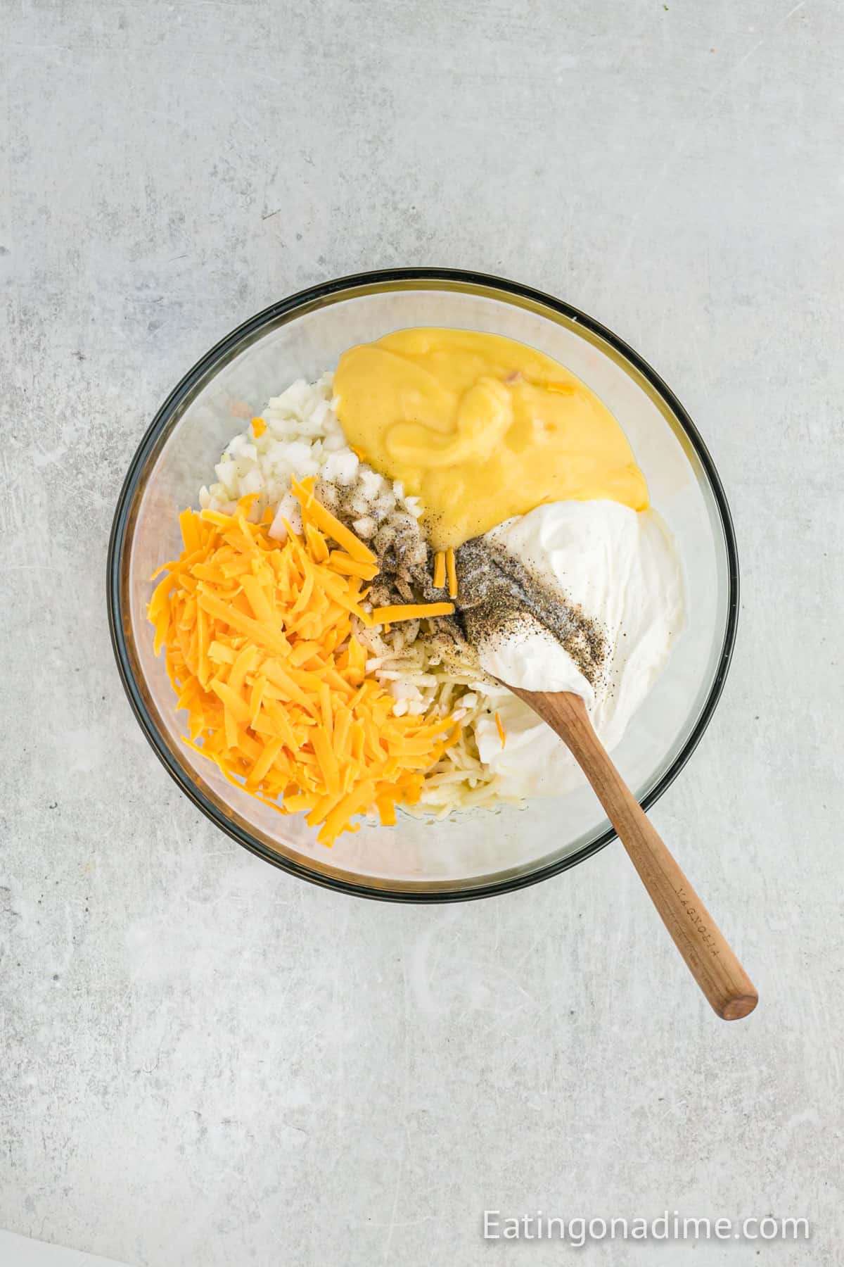 Combining the potato hashbrown ingredients in a bowl with a wooden spoon