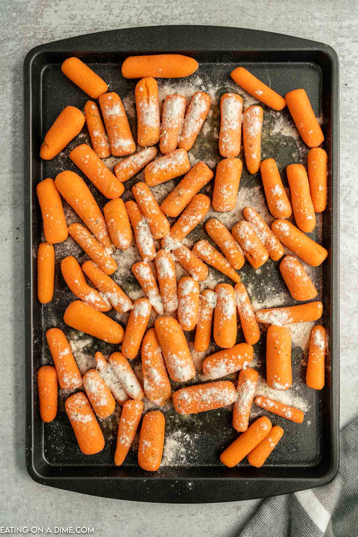 Ranch seasoning mix spread over the baby carrots on a baking sheet