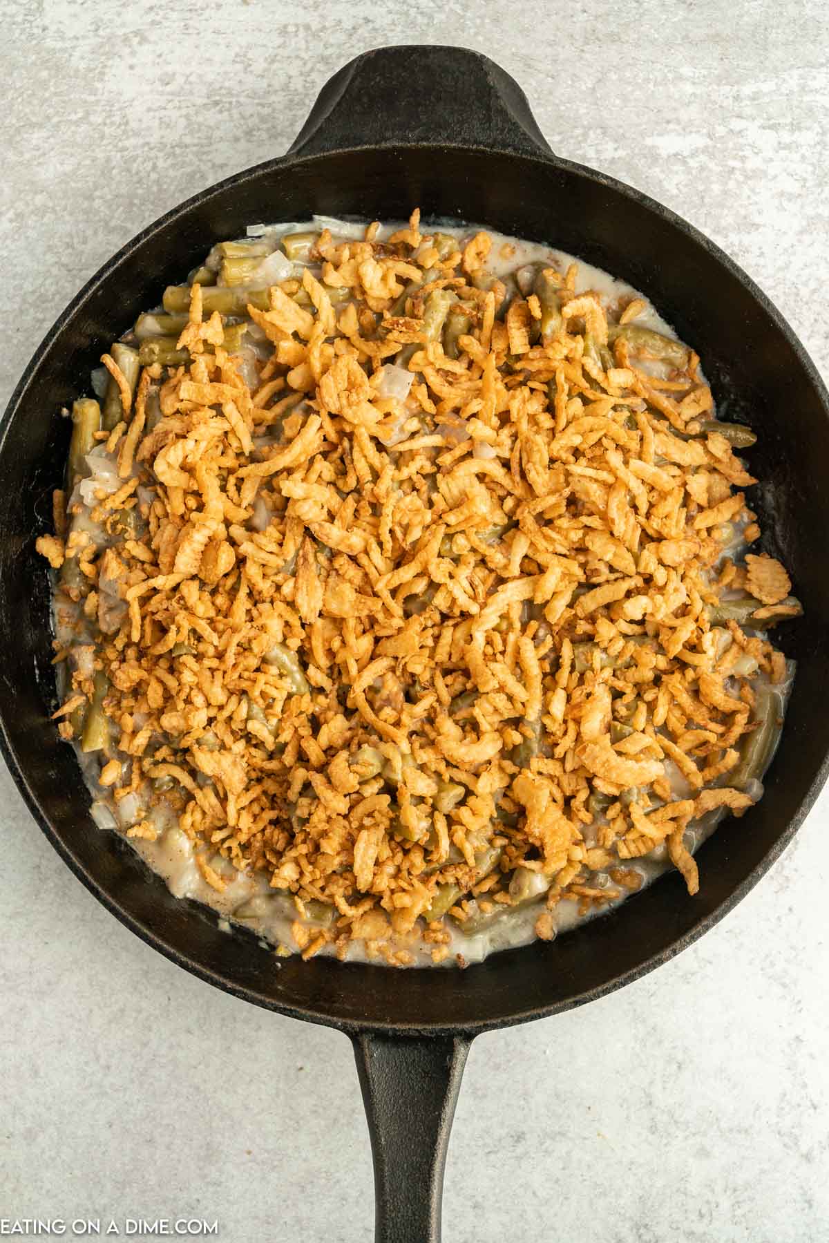 French Fried Onions topped with green bean casserole in a cast iron skillet