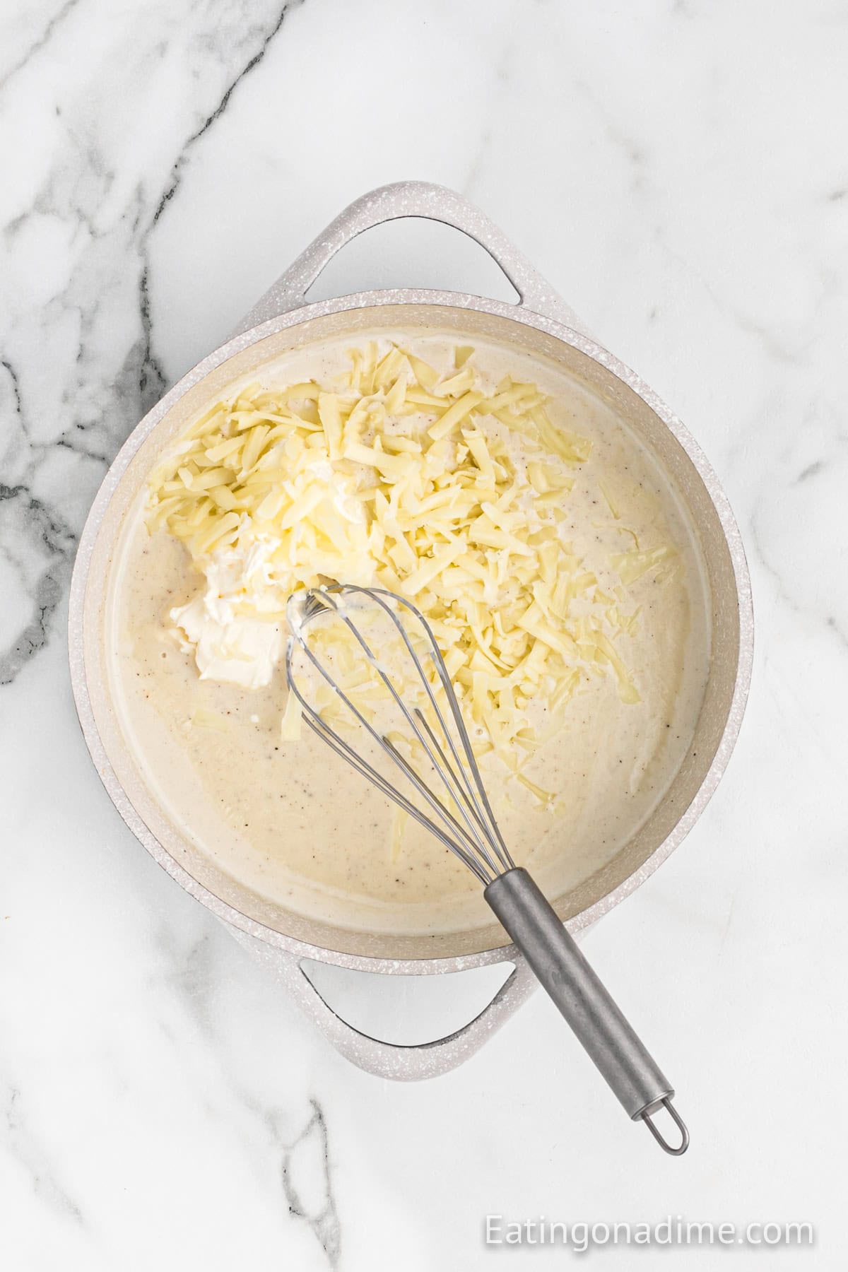 Mixing in shredded cheese in a creamy mixture in a large pot