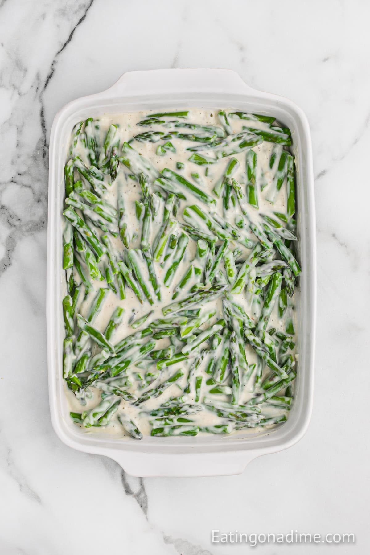 Diced asparagus in a baking dish in a creamy mixture