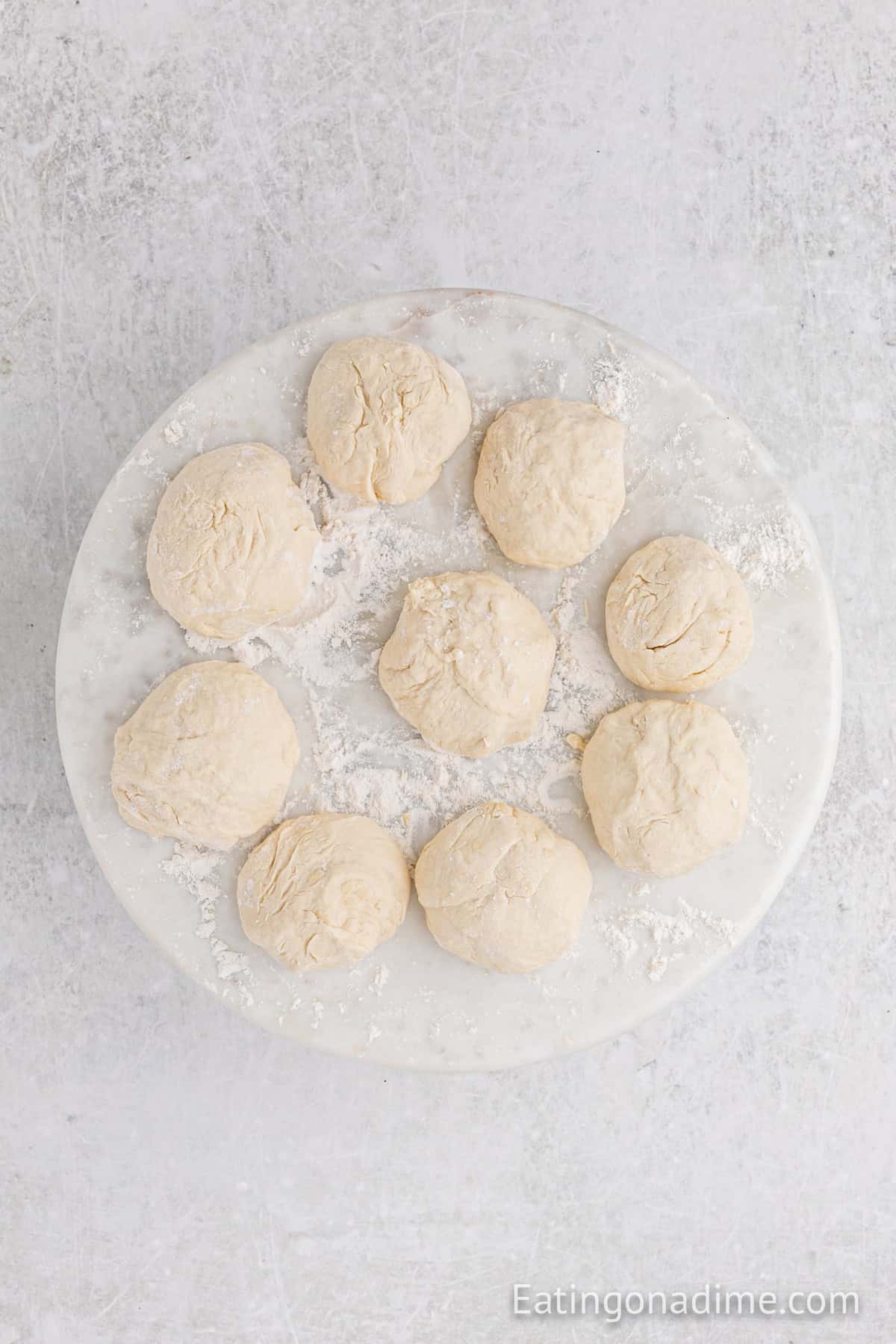 Dough divided into 9 round shaped balls on a platter