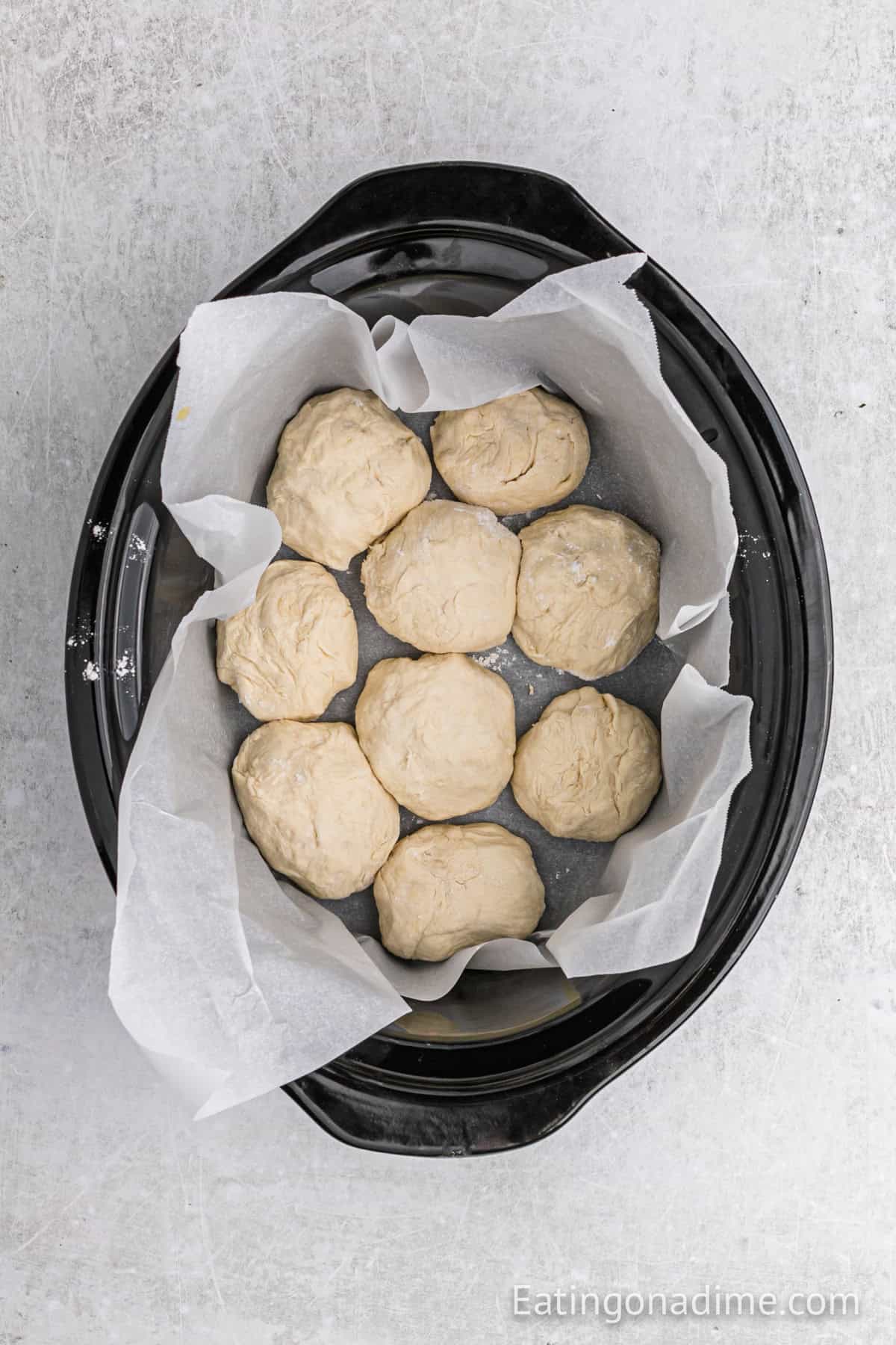 Dough balls placed in slow cooker lined with parchment paper