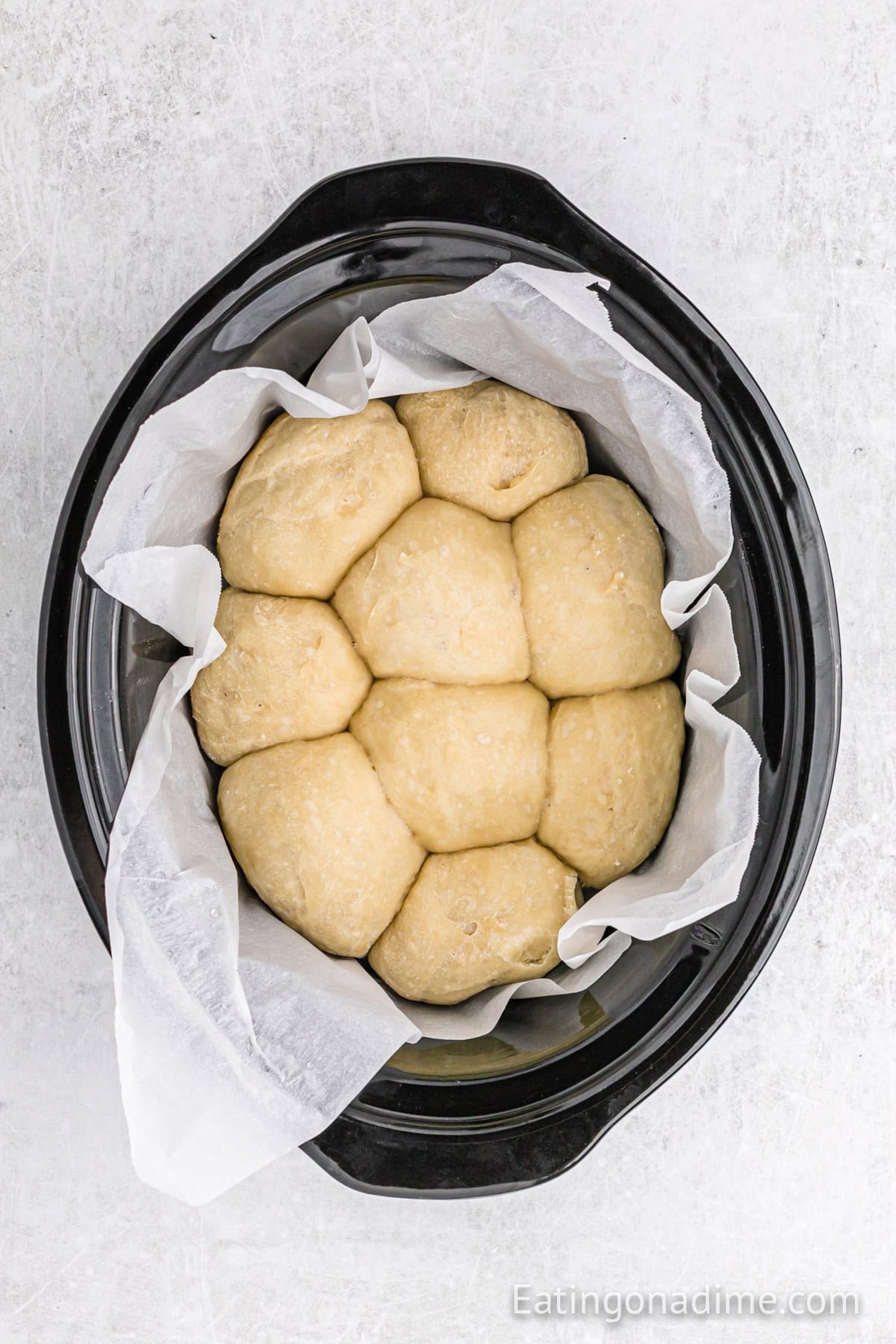 Cooked dinner rolls in the slow cooker lined with parchment paper