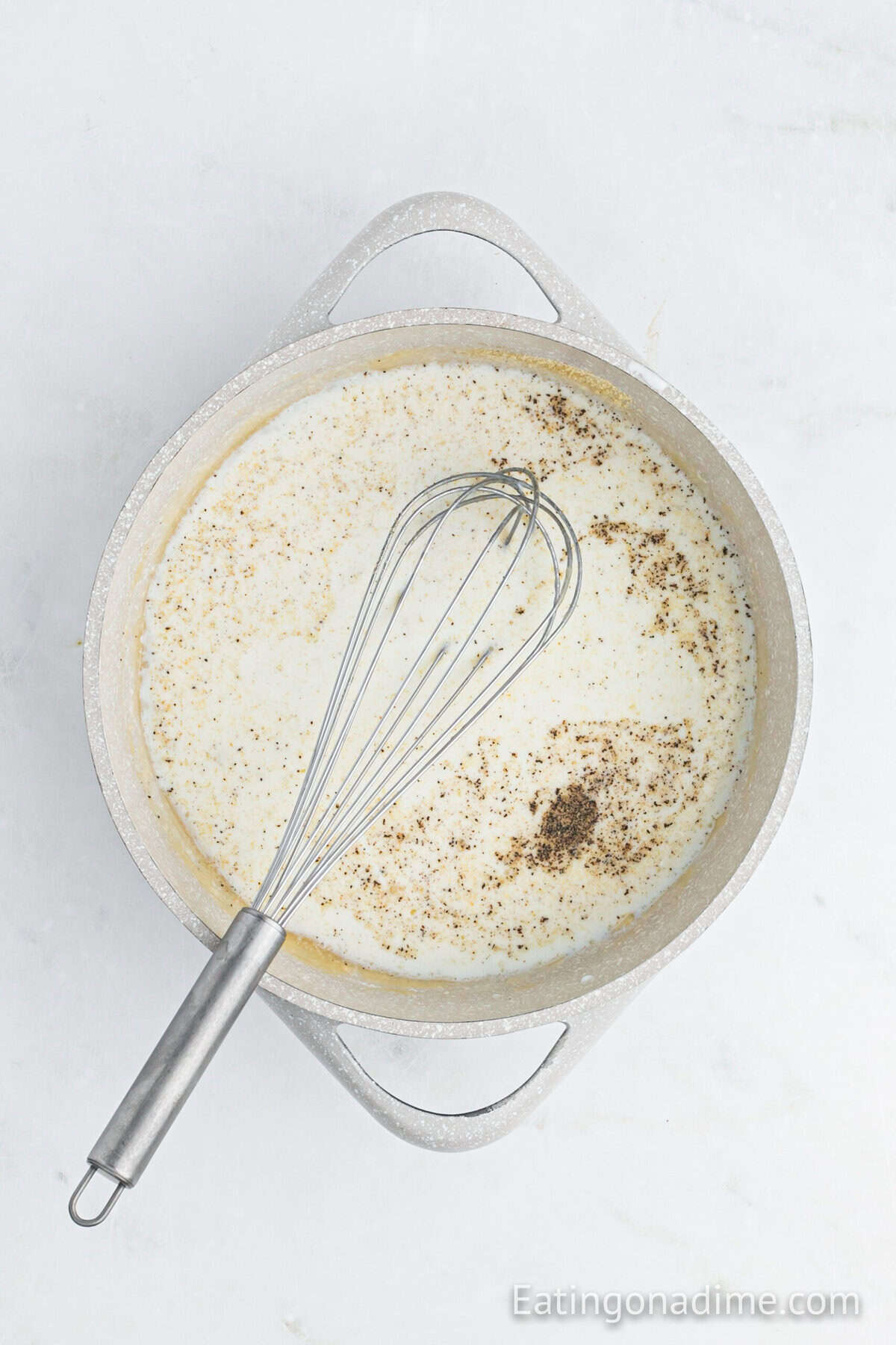 Milk mixture with seasoning in a large pot with a whisk