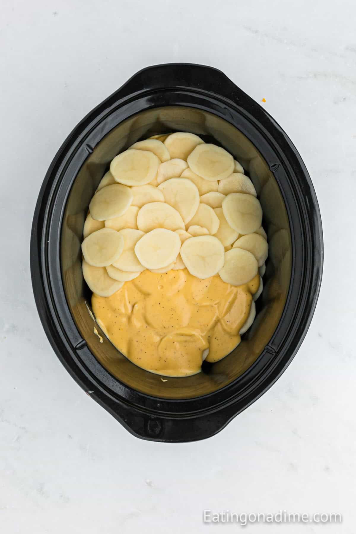 Slice potatoes in a slow cooker topped with melted cheese