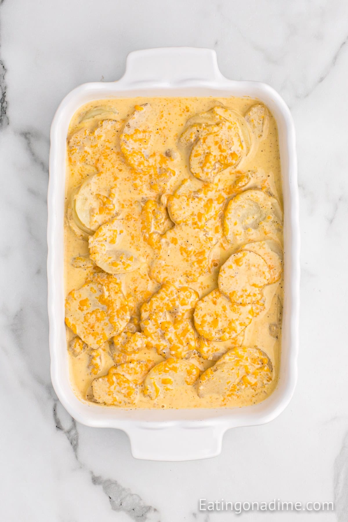 Cheesy mixture poured over the sliced potatoes in the casserole dish