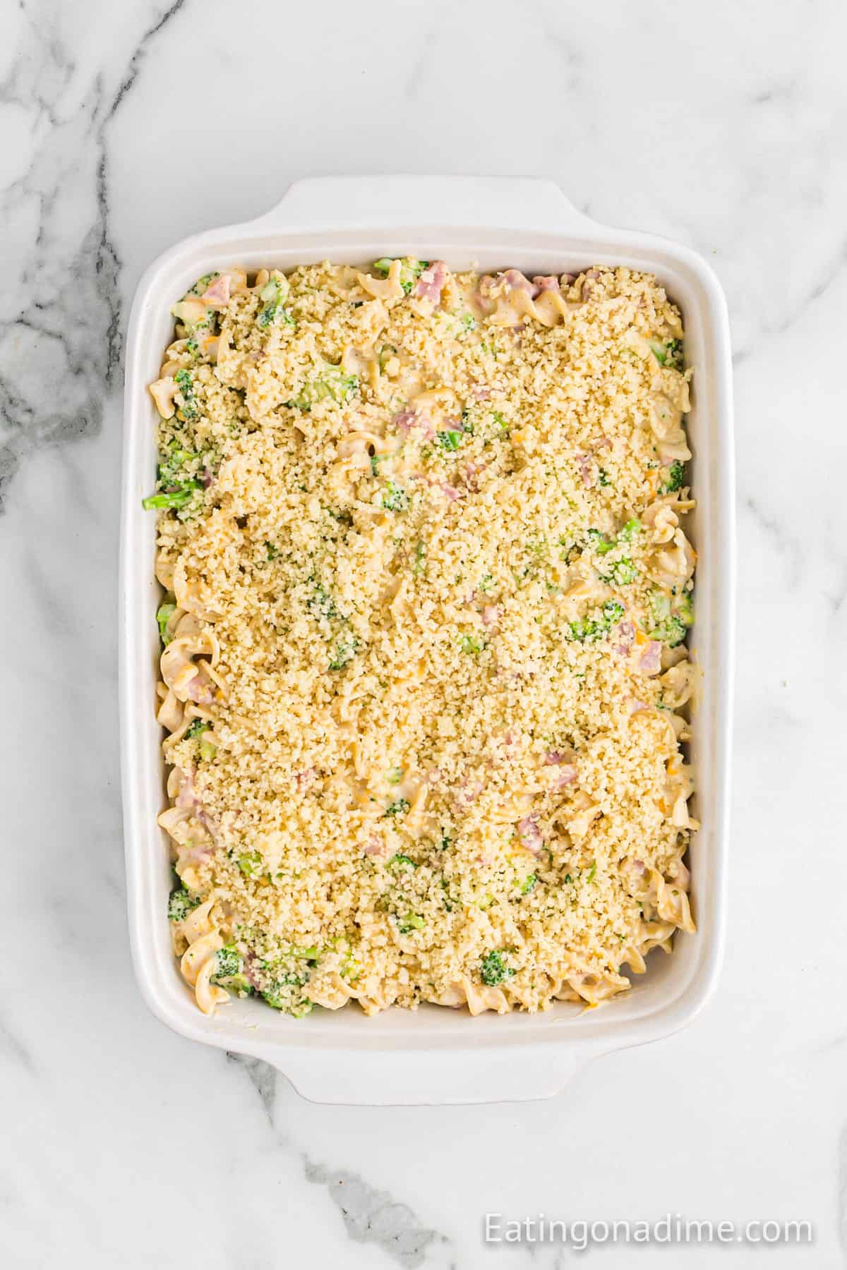 Topping the casserole with the breadcrumb mixture in a baking dish