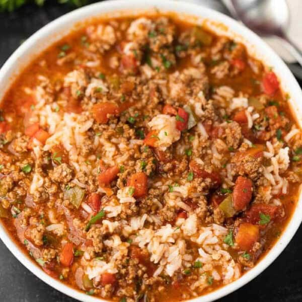 A bowl of hearty stuffed pepper soup, rich in ground beef, diced tomatoes, green bell peppers, rice, and herbs, creates a colorful and comforting dish when prepared with the Instant Pot. Perfectly crafted for cozy meals on a dark surface.