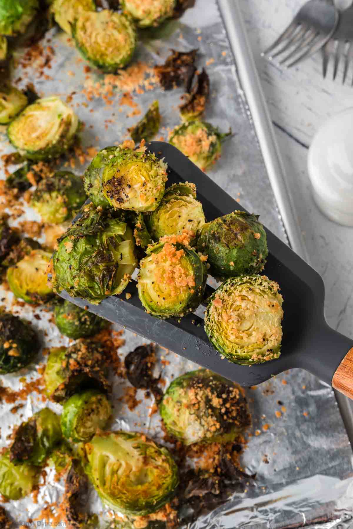 Roasted Brussel Sprouts on a baking sheet with a serving on a spatula