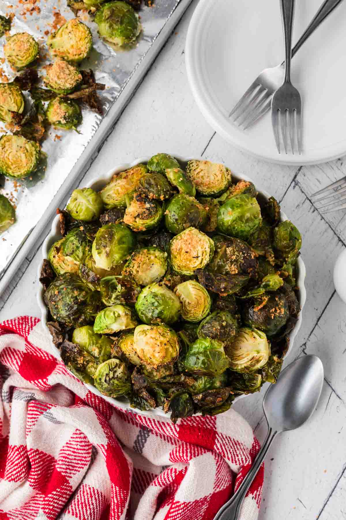 Roasted Brussel Sprouts in a bowl and baking sheet of Brussel Sprouts on the side