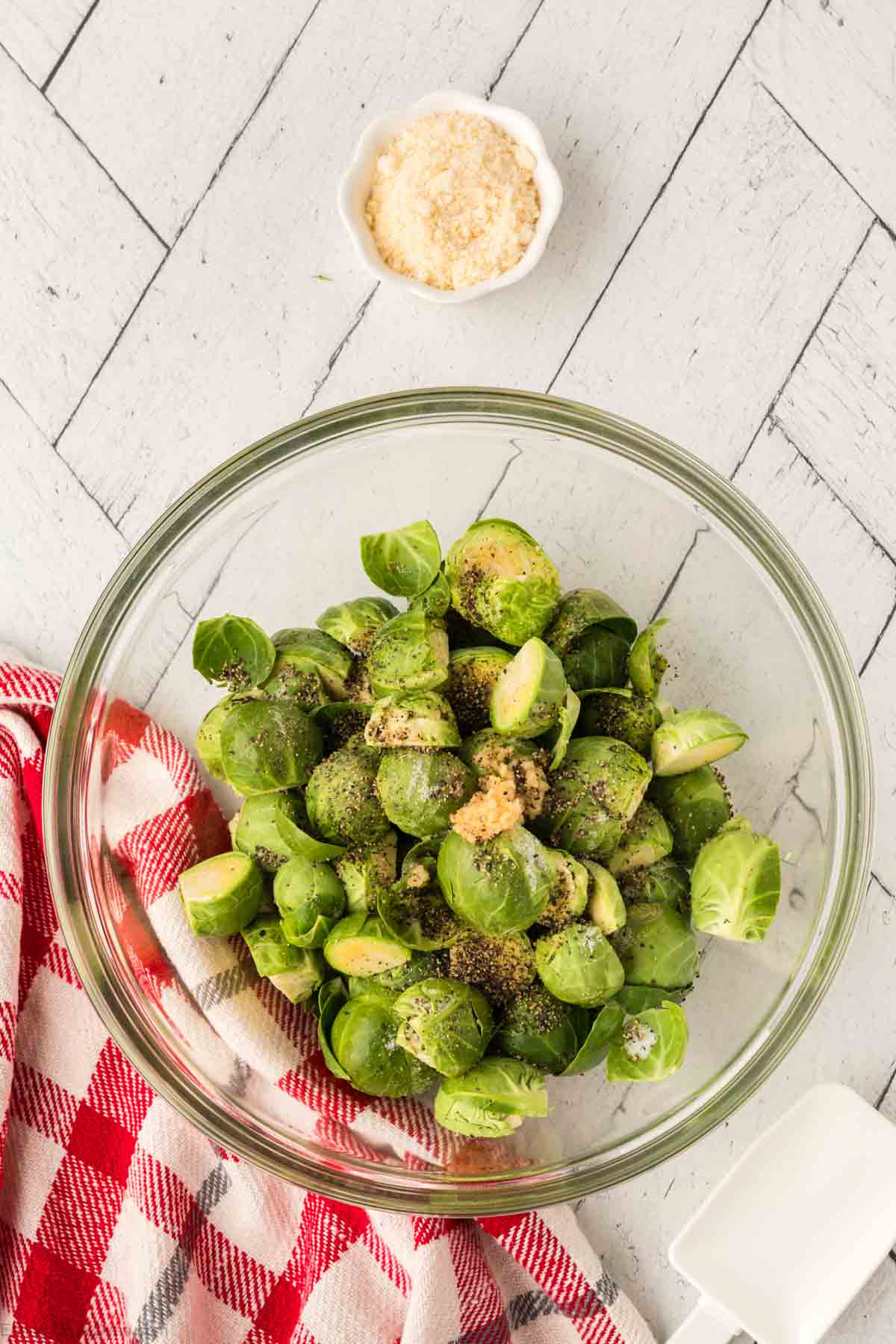 Fresh Brussel Sprouts in a bowl topped with seasoning and minced garlic