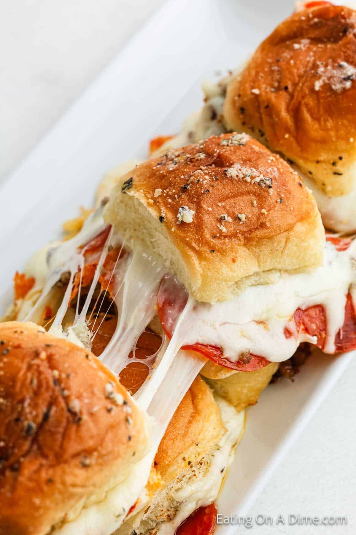 Pizza Sliders stretched to show the melty cheese layered with pepperoni