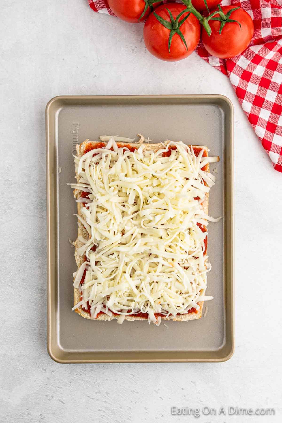 Bottom Rolls on a baking sheet topped with pizza sauce and shredded cheese