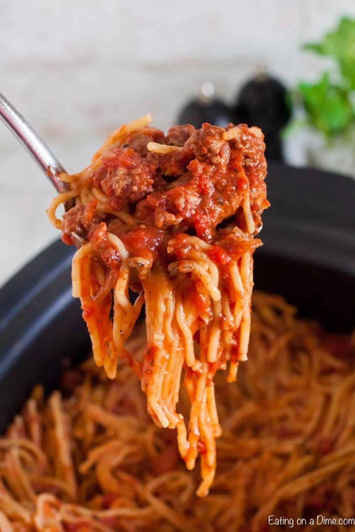 Spaghetti in the slow cooker with a serving on a ladle