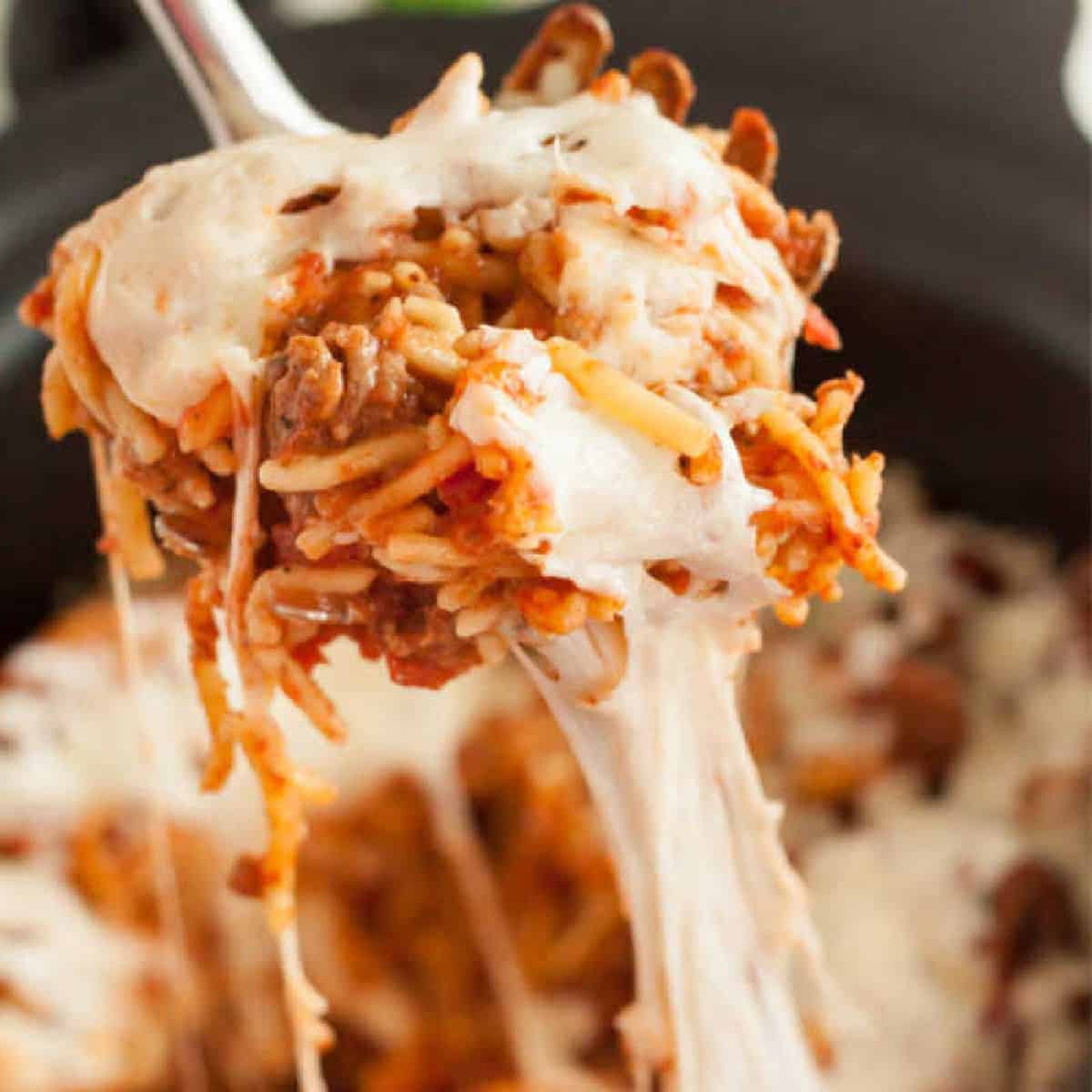 Spaghetti casserole in a slow cooker with a serving on a ladle