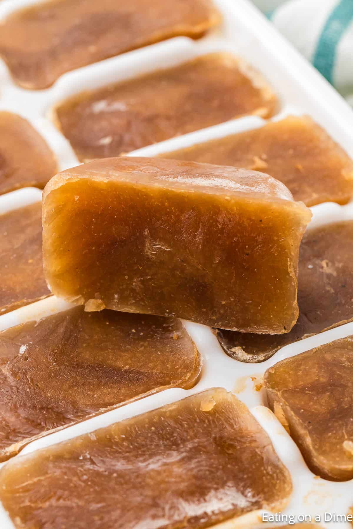 Ice cubes of gravy topped of ice tray of frozen gravy cubes