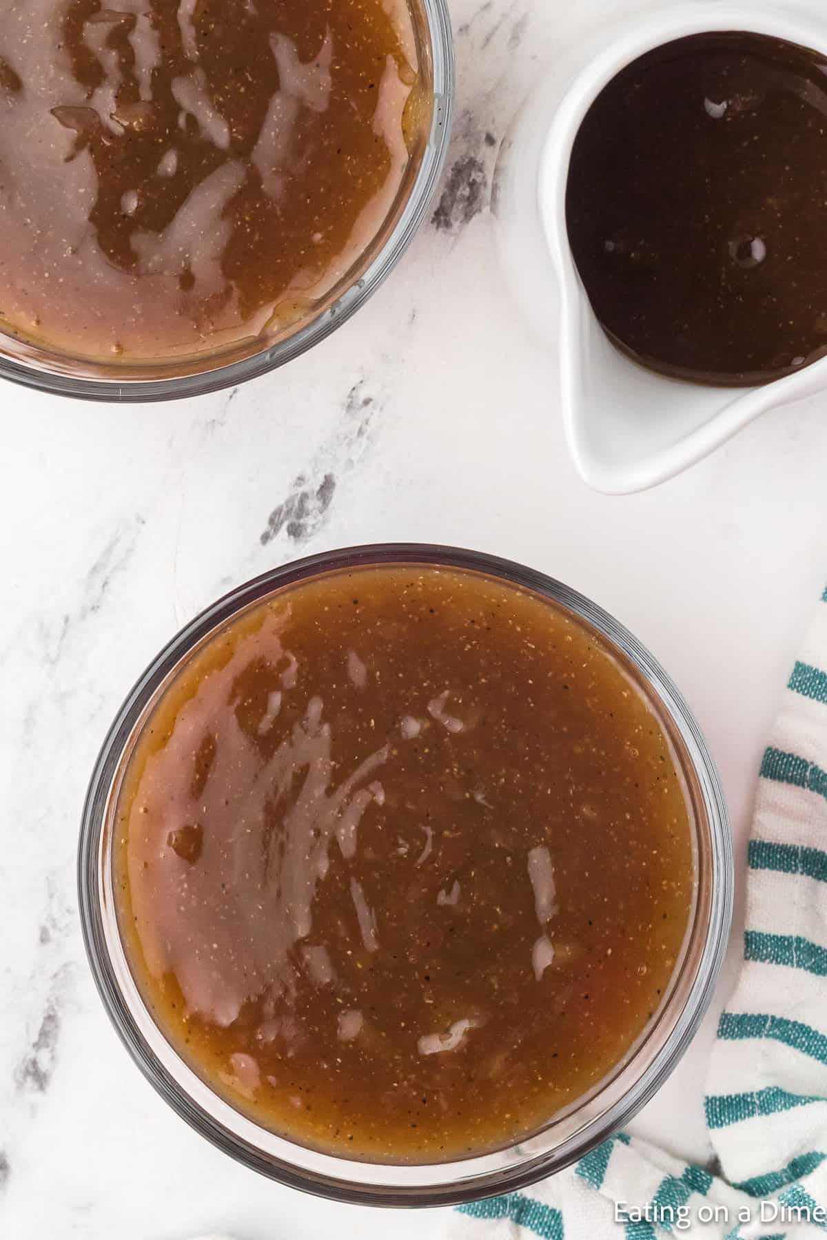 Two bowls of brown gravy with a gravy boat with gravy