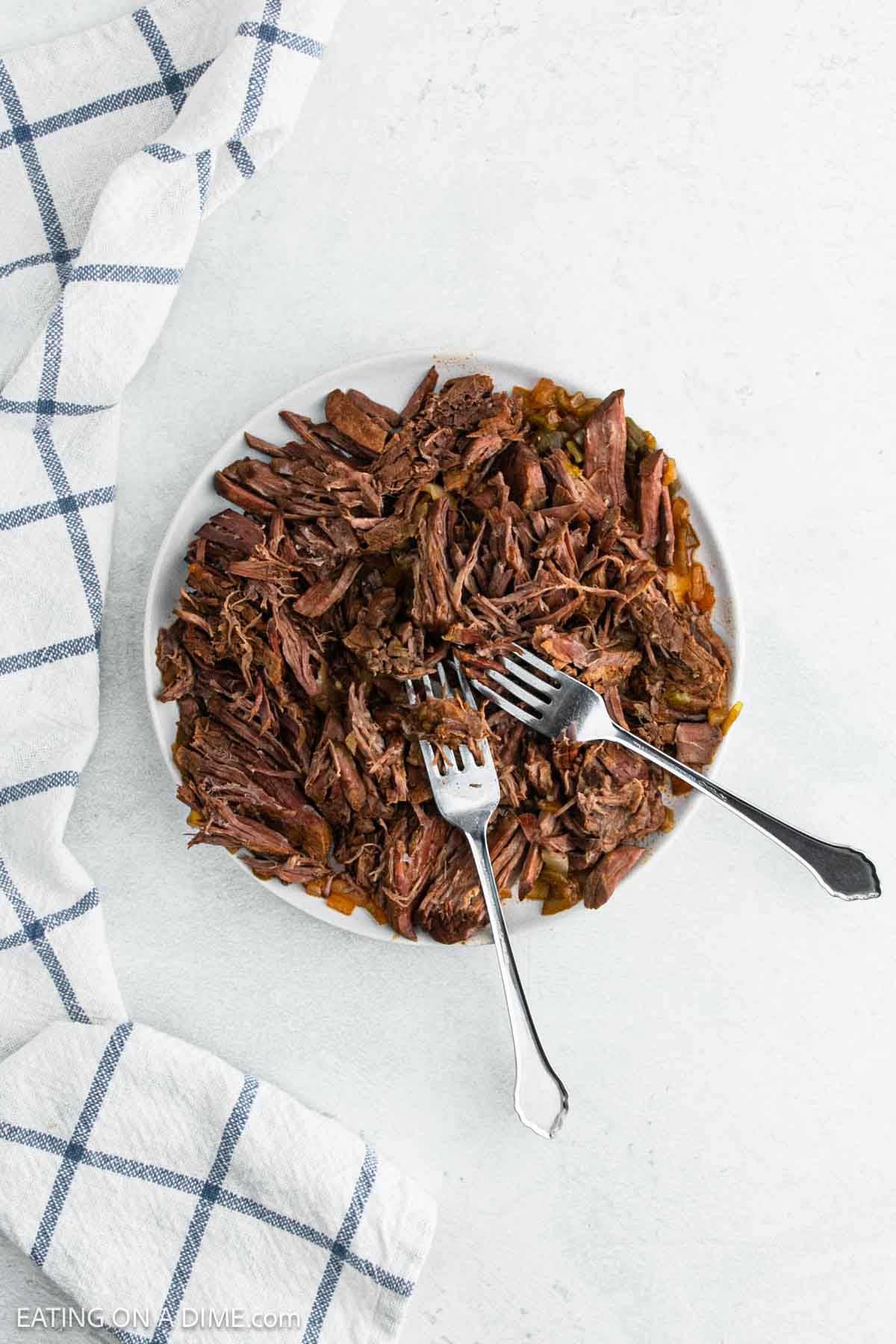 Shredded beef on a plate with two forks