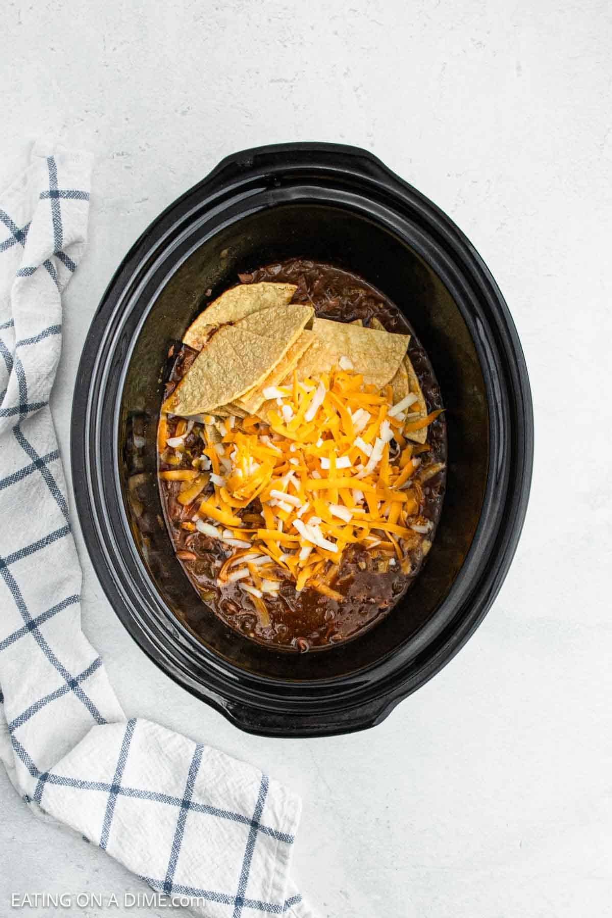 Shredded beef in the crock pot with shredded cheese on top with cut corn tortillas