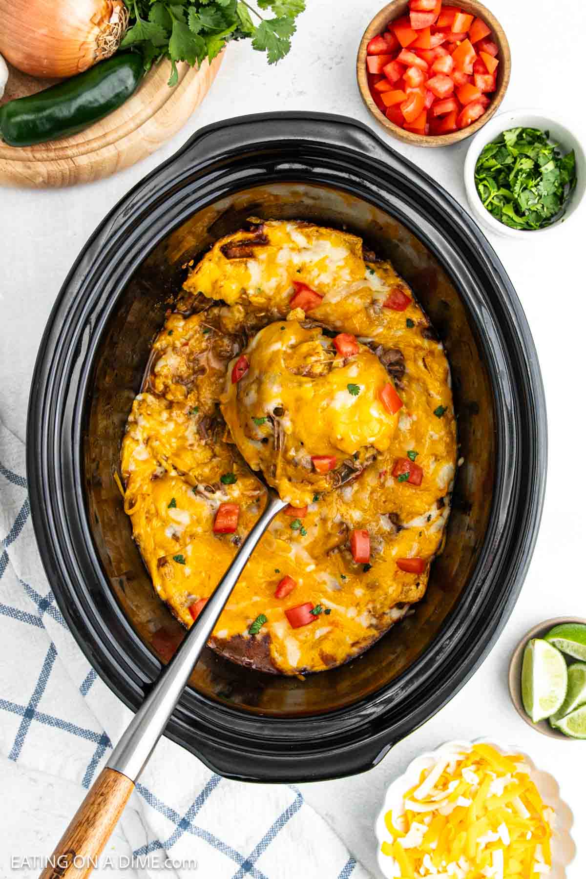 Beef Enchiladas in the slow cooker topped with melted cheese and diced tomatoes