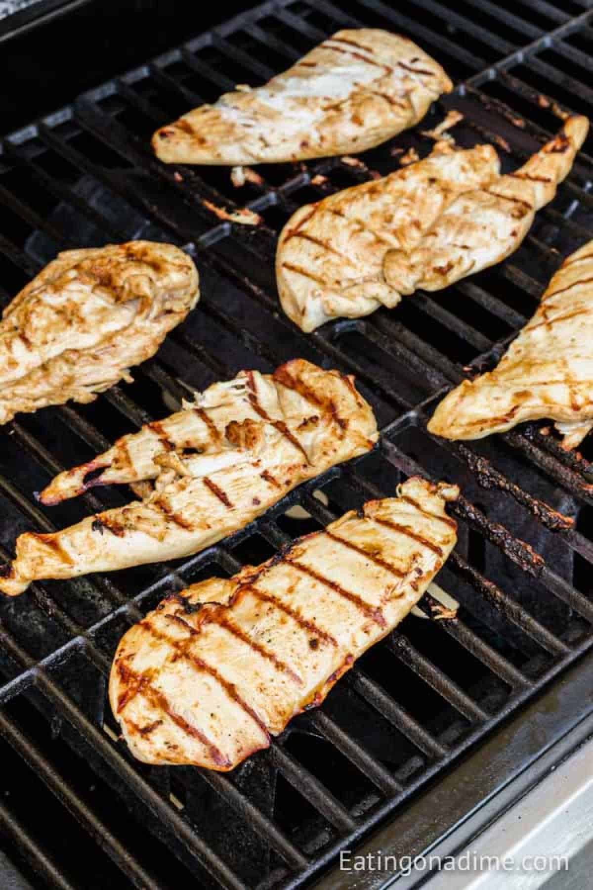 Grilled chicken fajitas with char marks sizzle on a barbecue grill. The evenly spaced pieces boast a golden-brown hue, capturing the essence of outdoor cooking. This tantalizing scene is courtesy of Eatingonadime.com.