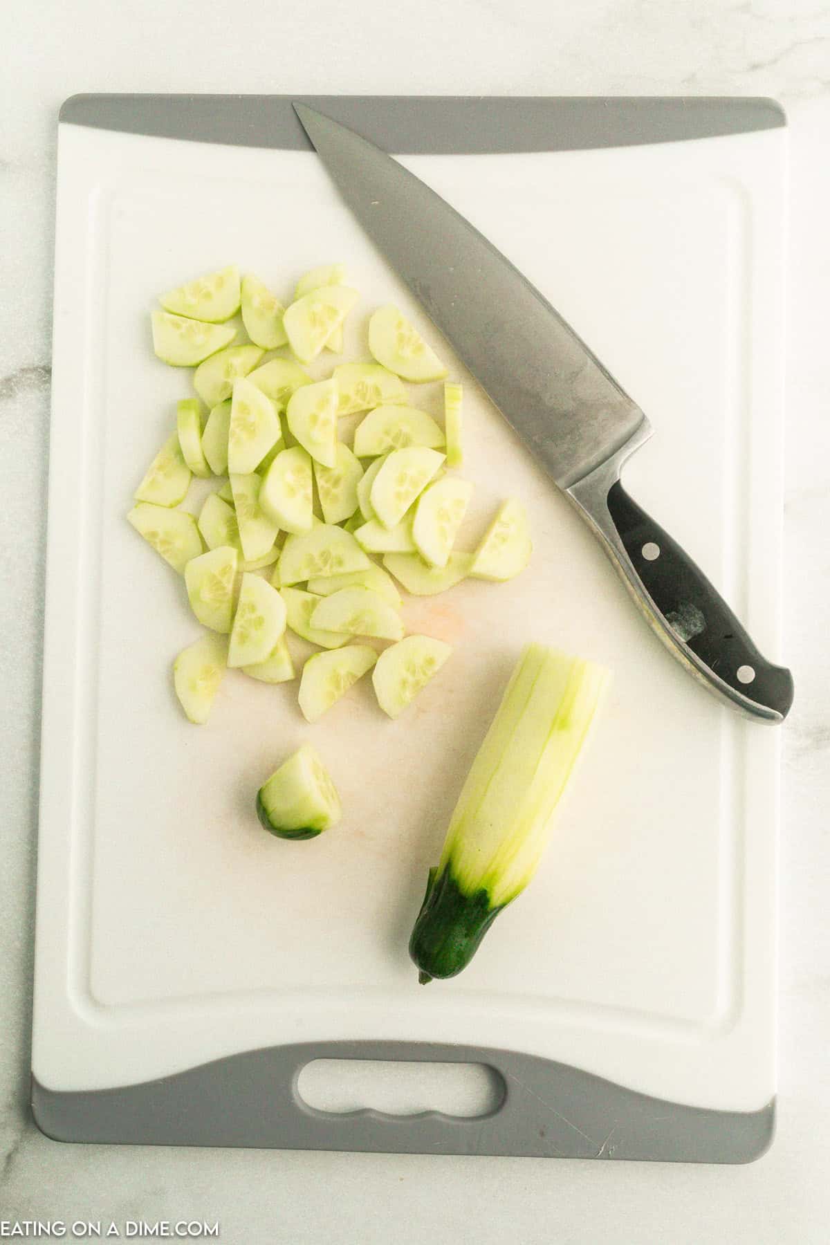 Slice cucumber on a cutting board with a knife on a cutting board