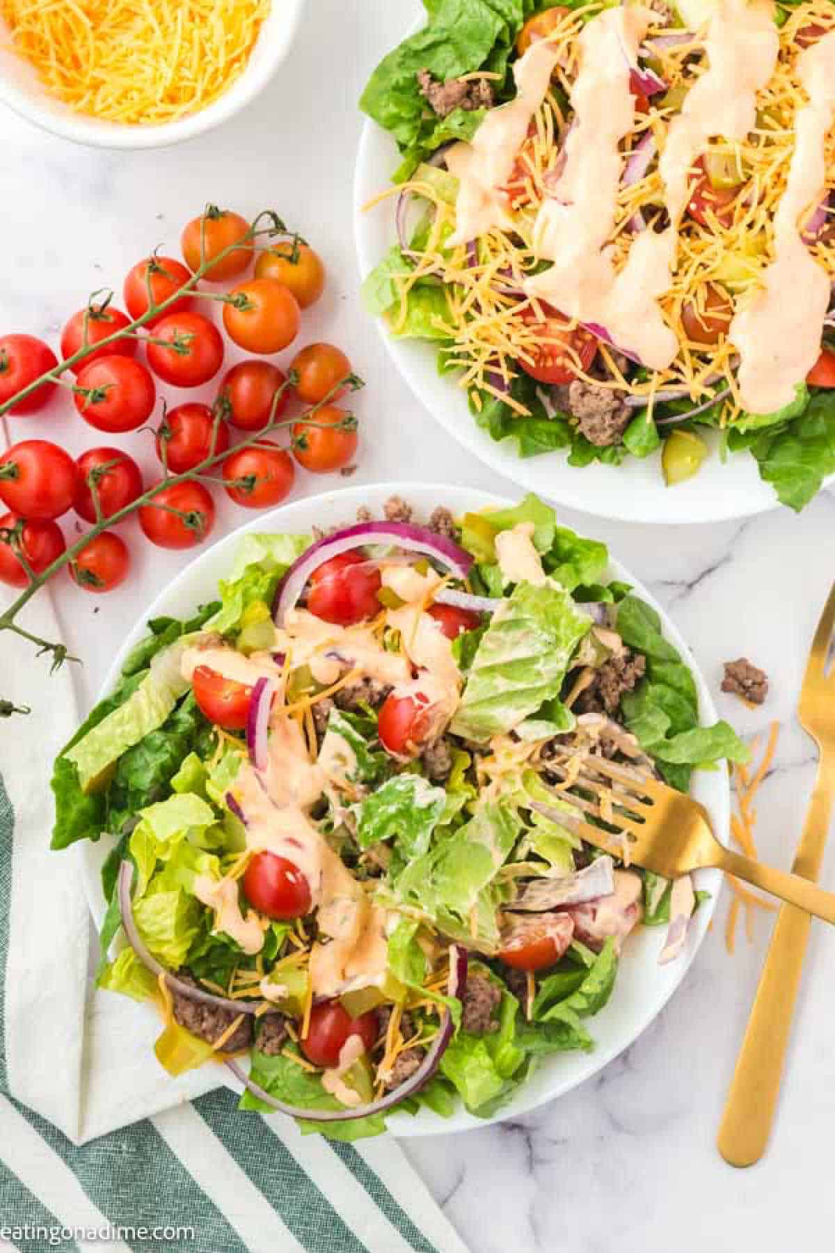 big mac salad on a plate with cherry tomatoes on the side.