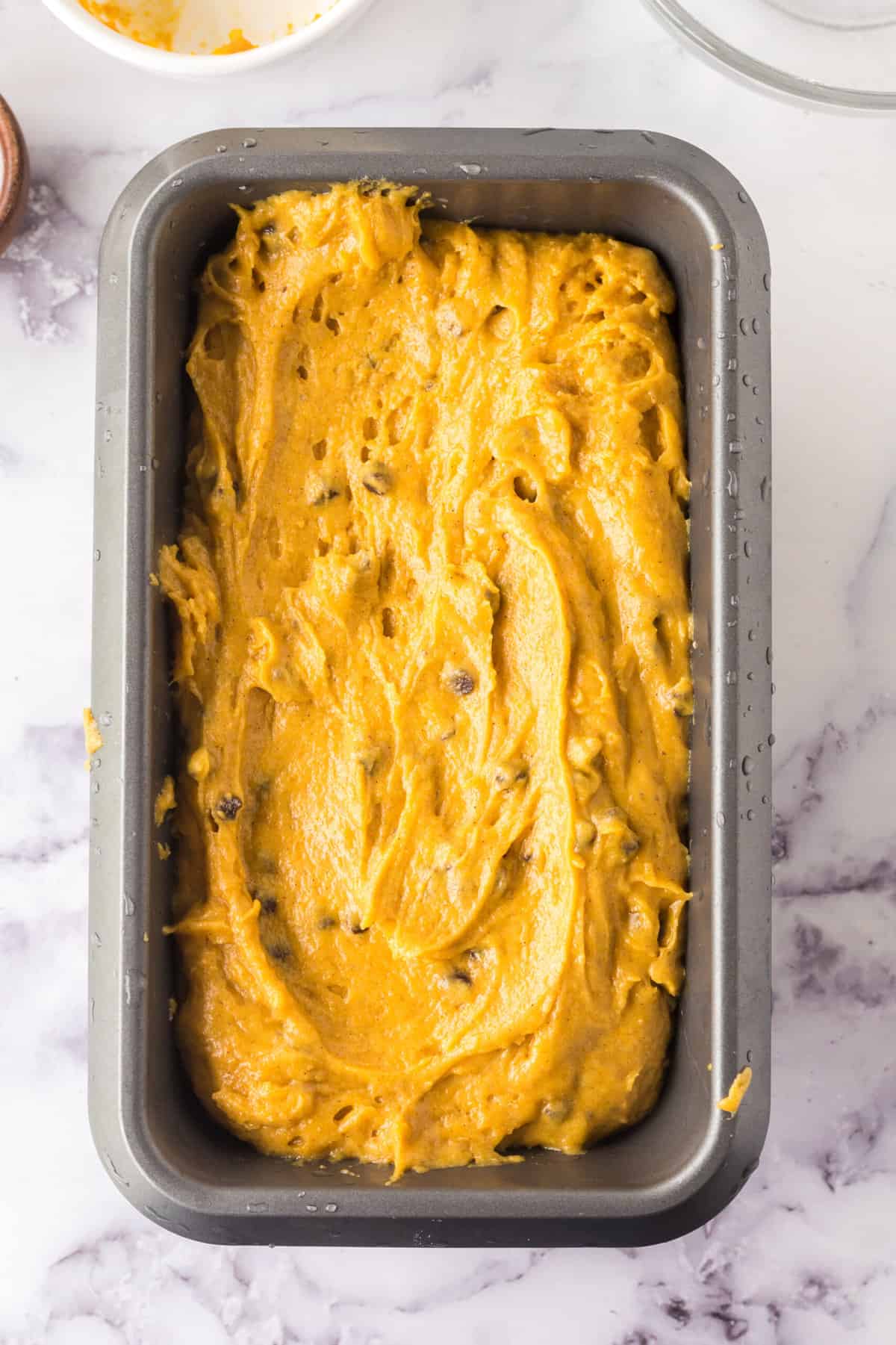 Spreading the pumpkin chocolate chip bread batter in a loaf pan