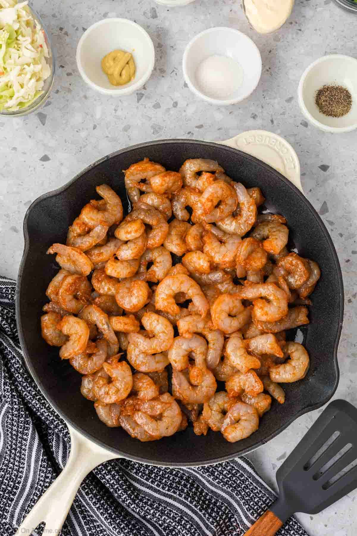 Seasoned shrimp in a cast iron skillet with a side of small bowls of mustard, salt and pepper