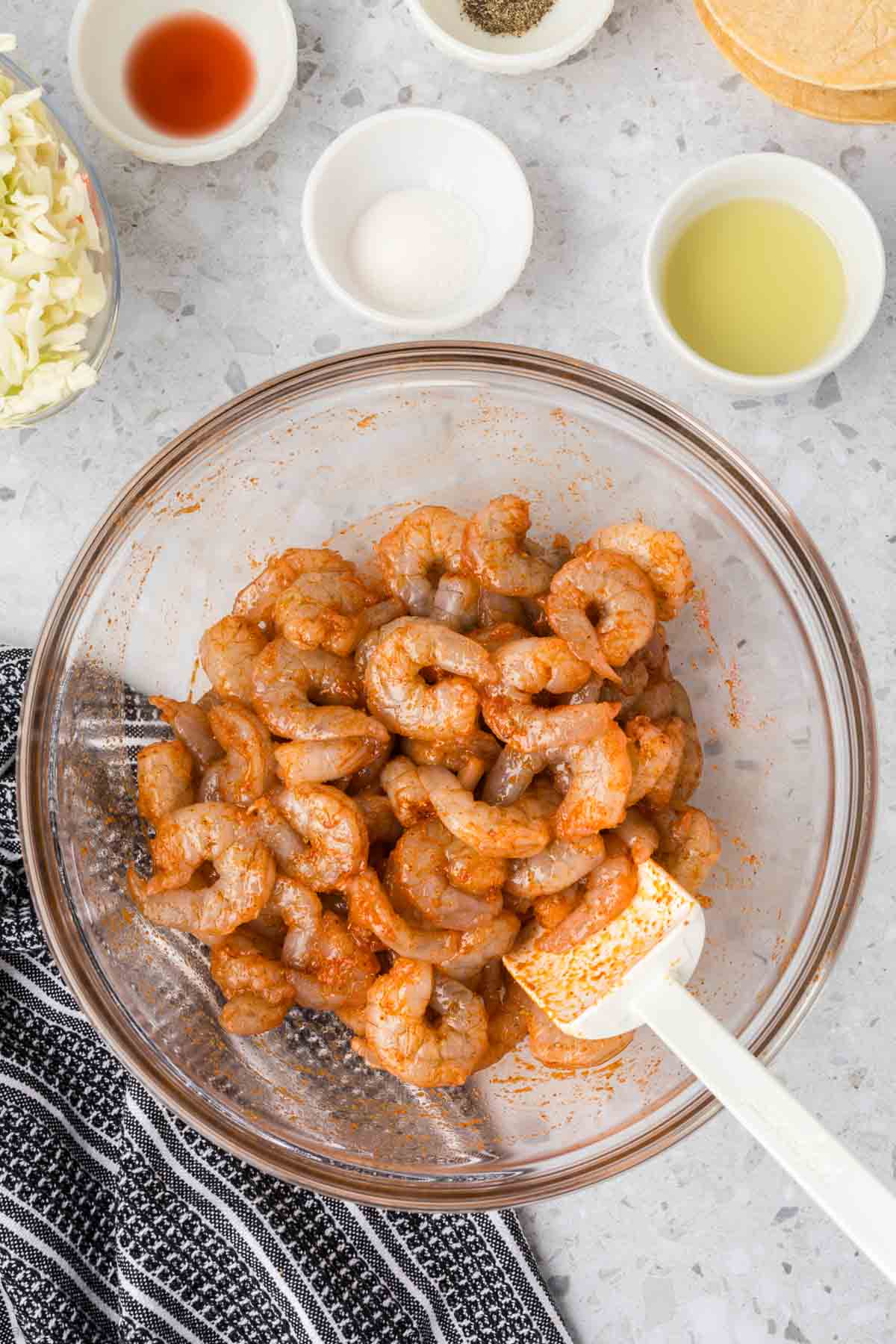 Combining the shrimp with the seasoning and oil in a bowl with a spatula