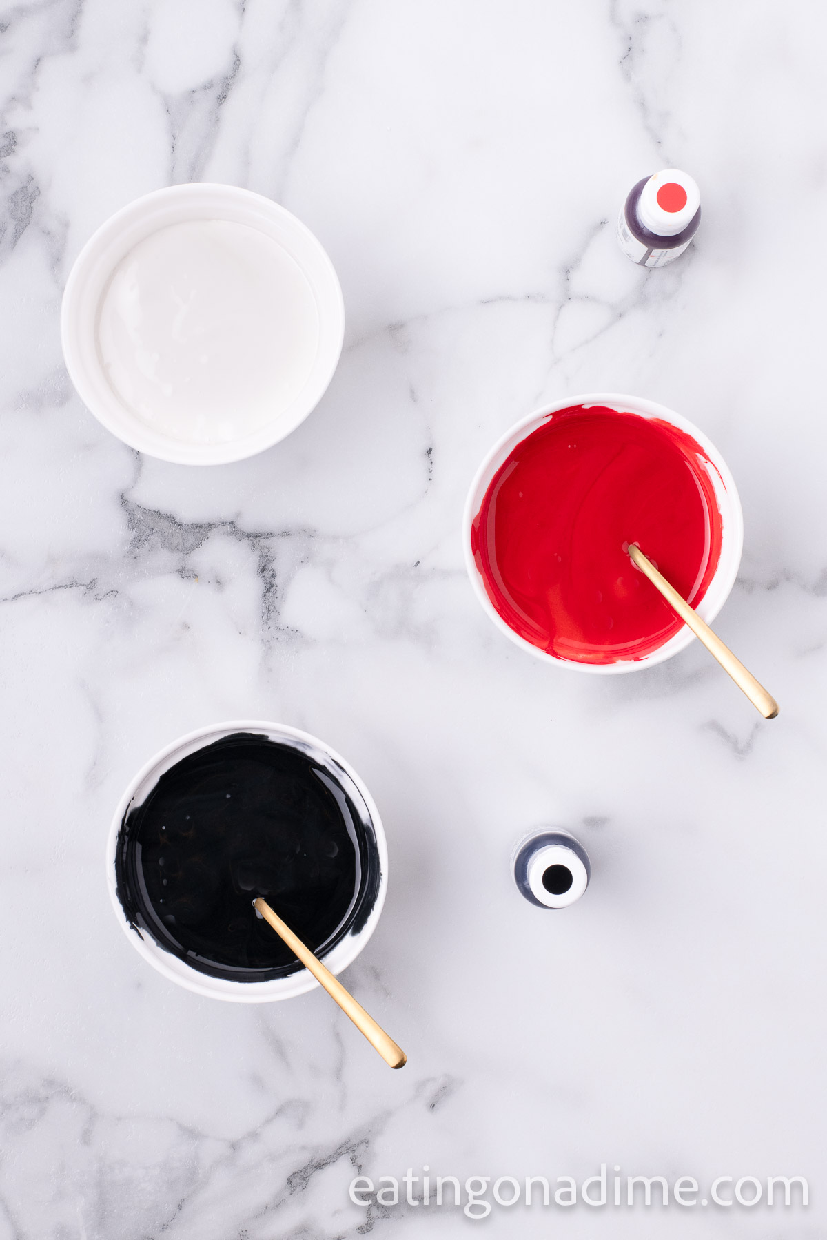 Black icing, red icing and white icing in 3 different bowls