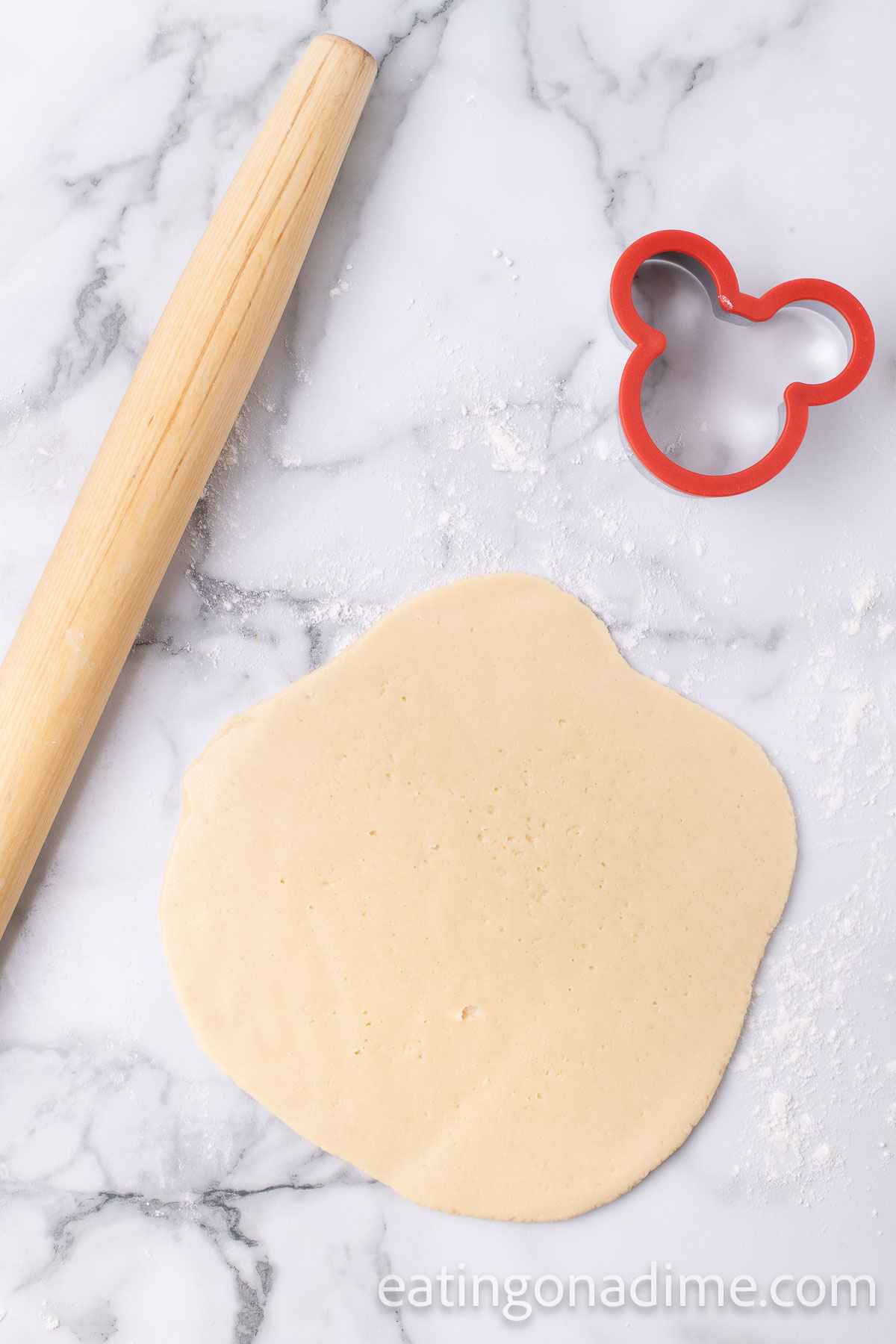 Rolling the dough out with a rolling pin and a Mickey Mouse Cookie Cutter on the side