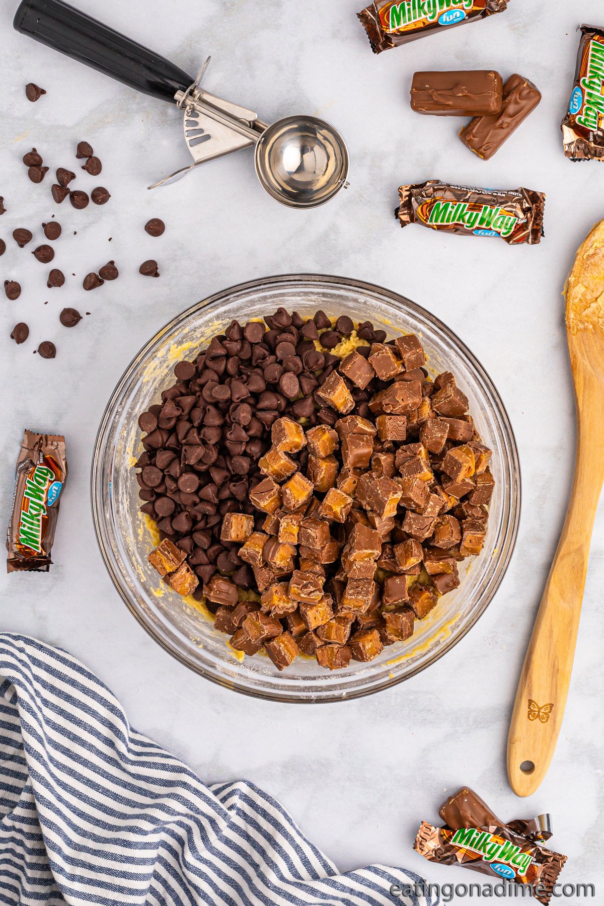 Adding in chocolate chips and chopped Milky Way in a bowl with the cookie dough batter